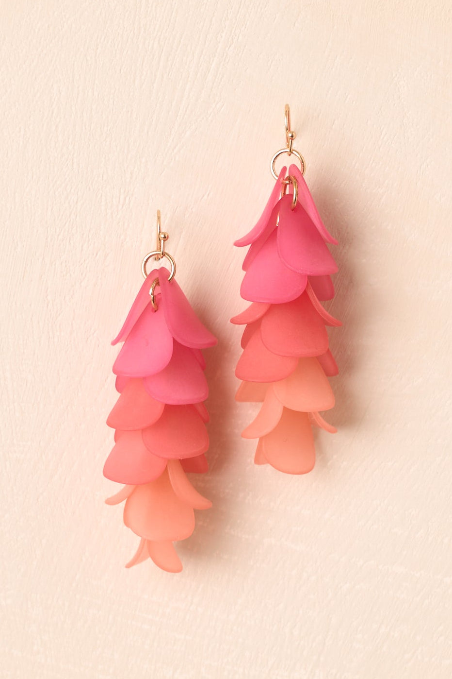 Close-up of the layered petal shapes and pink-to-coral gradient detailing on the statement earrings.