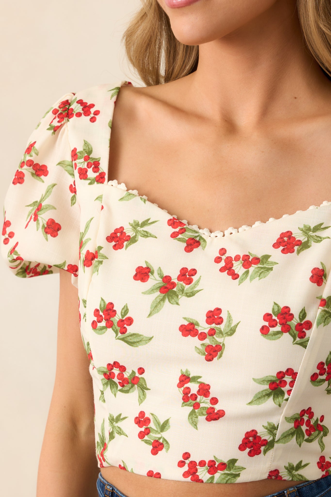 A closer view of the intricate red and green floral berry print, showcasing the soft ivory lace trim along the sweetheart neckline.