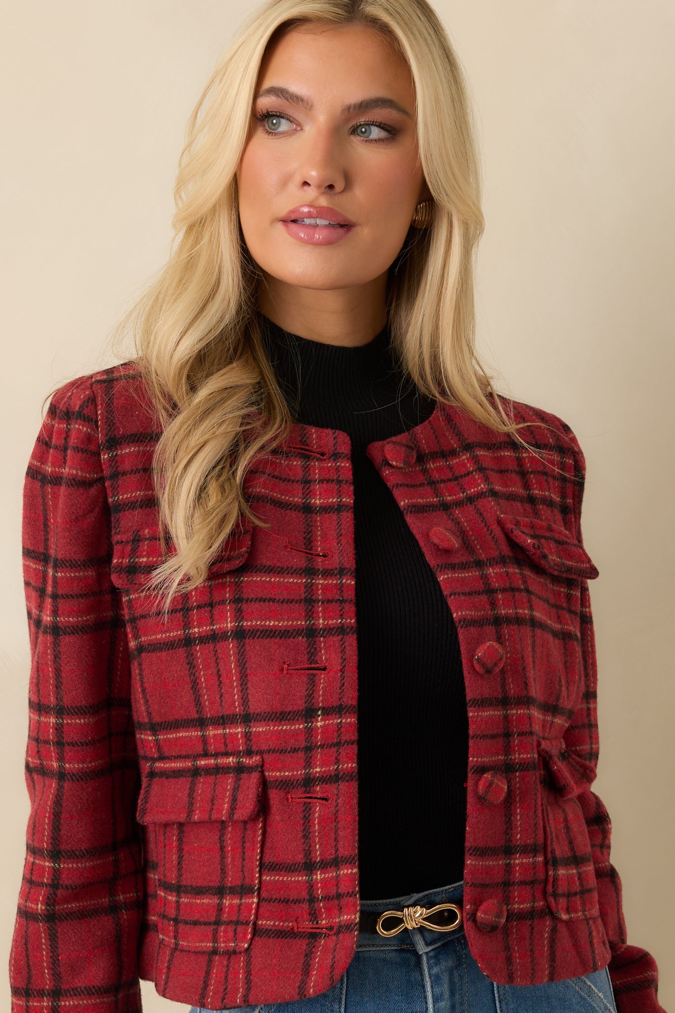 Close-up view of red plaid jacket showing button closures and flap pockets.