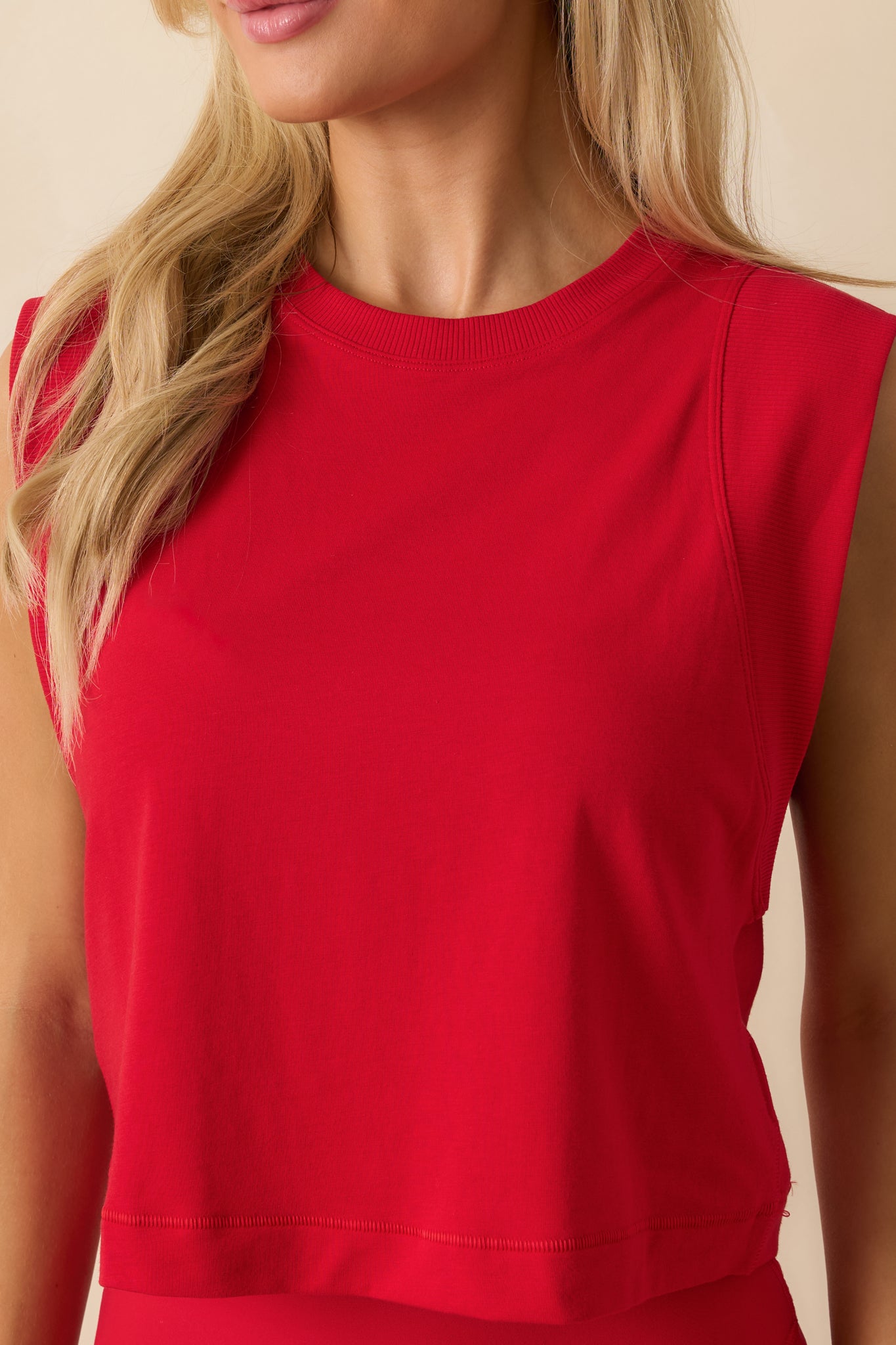 Close up of a red sleeveless cropped tank top with a crew neckline and relaxed fit, shown in soft athleisure fabric.