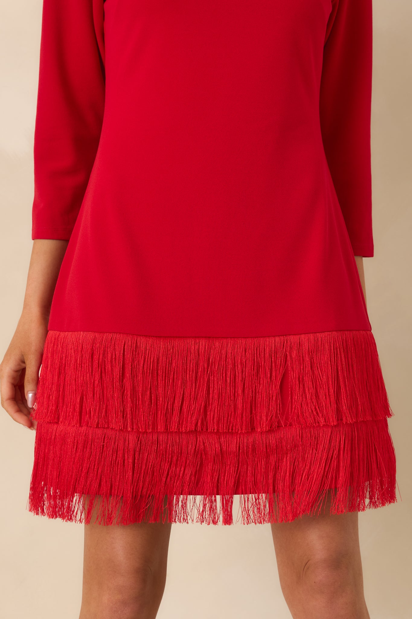 Tight view of the red woven fabric and tiered fringe hem, showing texture, stitching, and fabric drape.