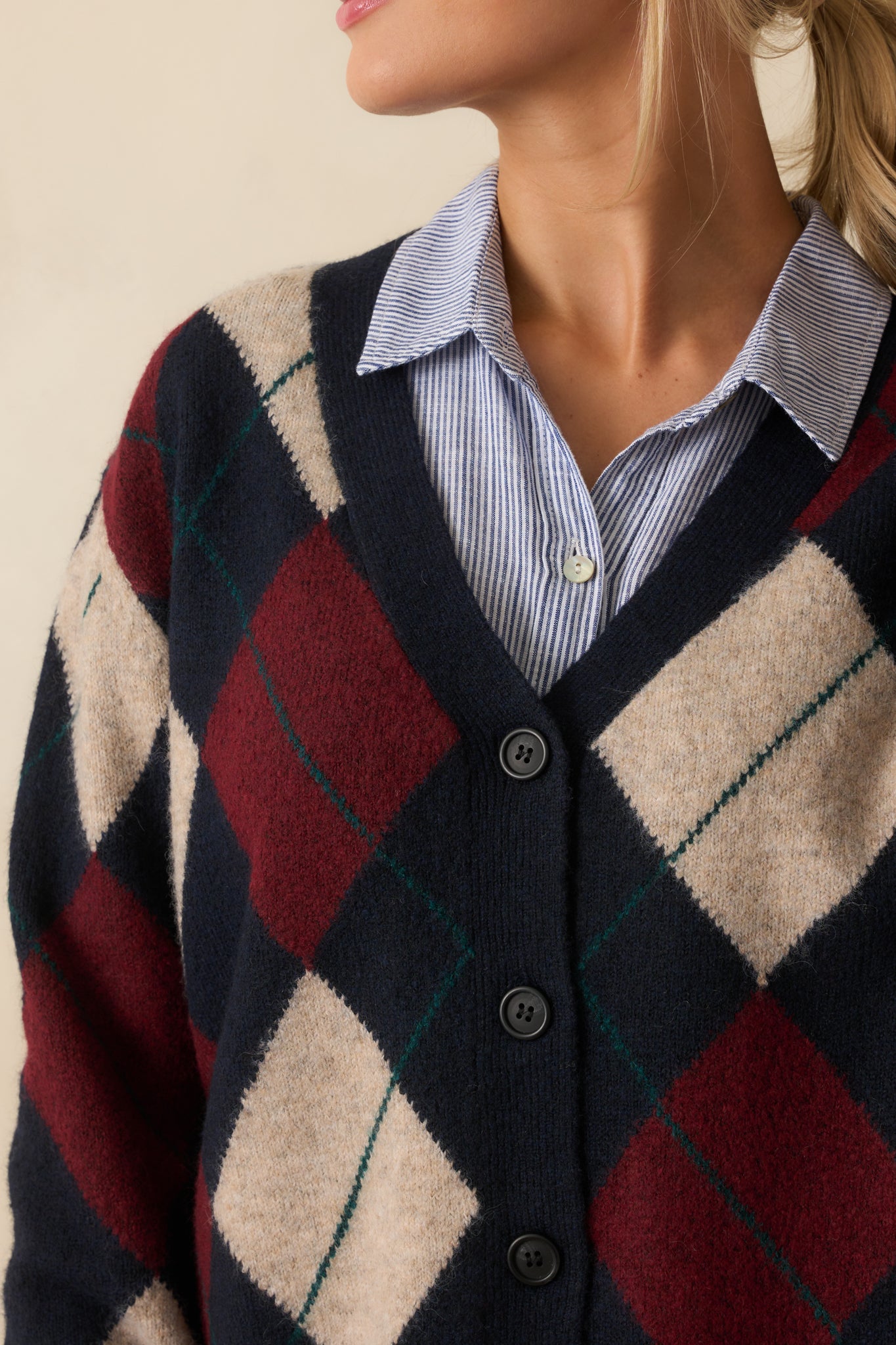 Close-up showing the ribbed hems, button front, and argyle knit on the navy cardigan.