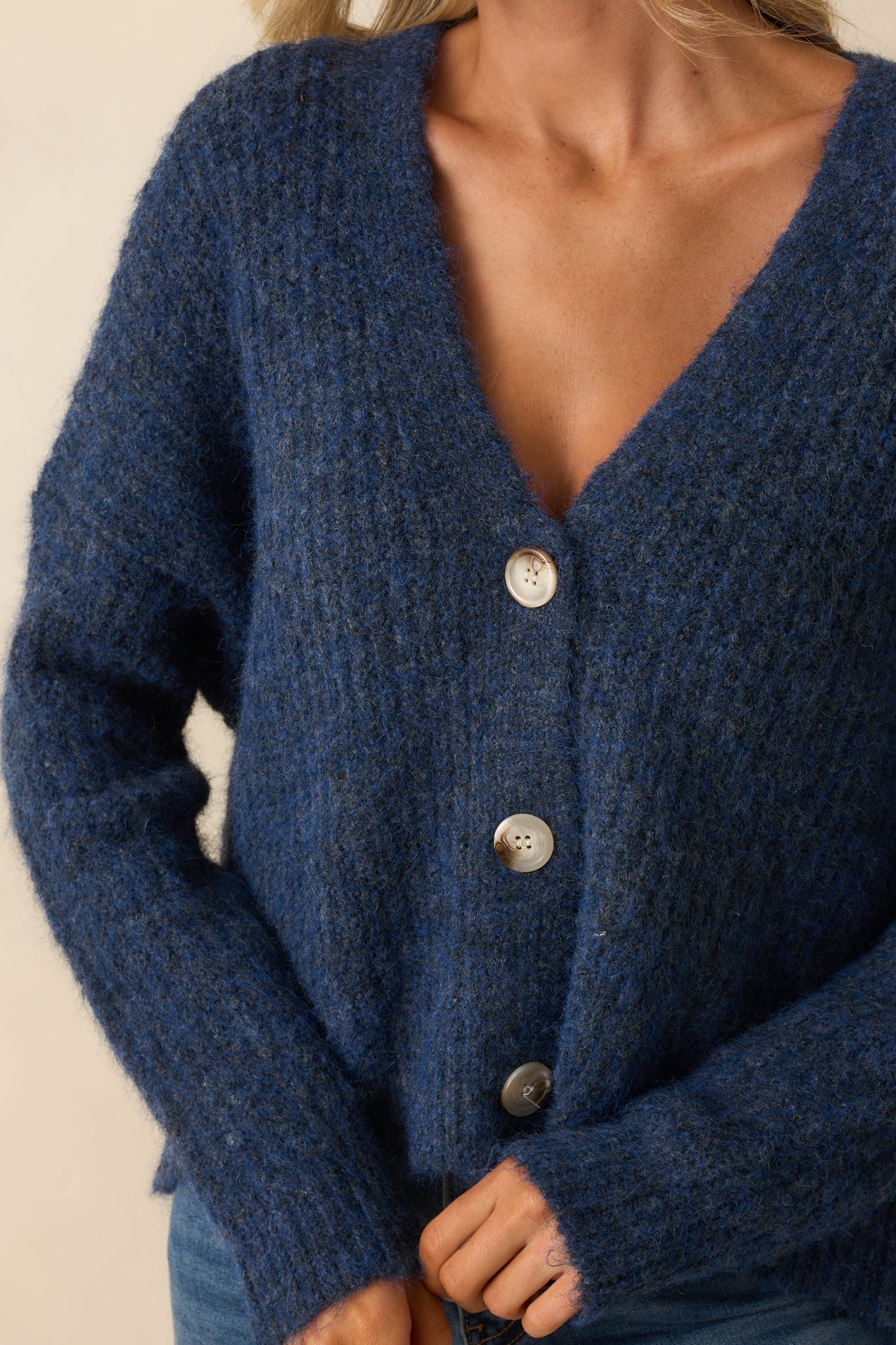 Close-up of the ribbed knit texture and tortoise shell buttons on the navy cardigan.