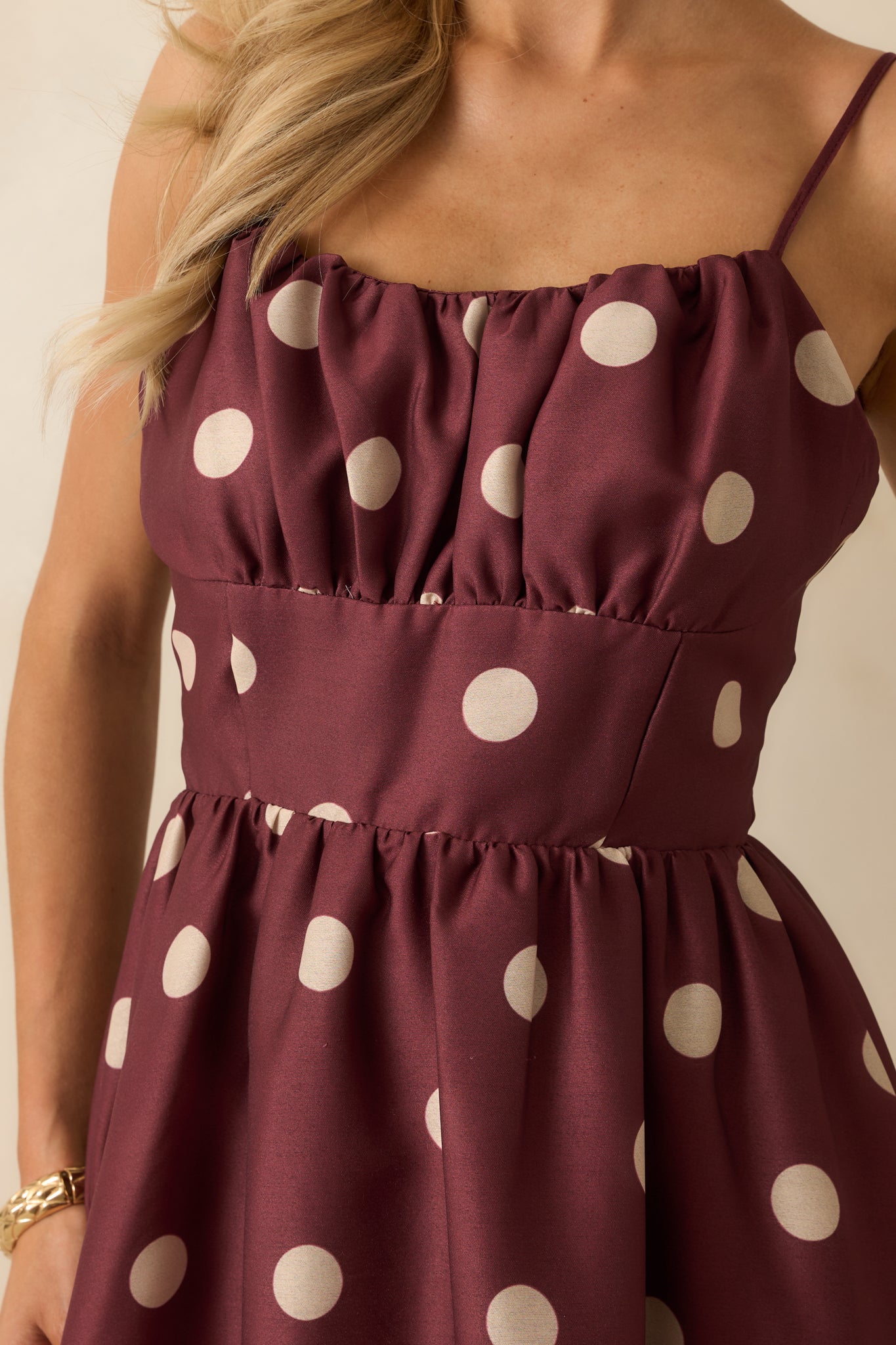 Close-up showing ruched bust, adjustable spaghetti straps, and polka dot pattern texture.