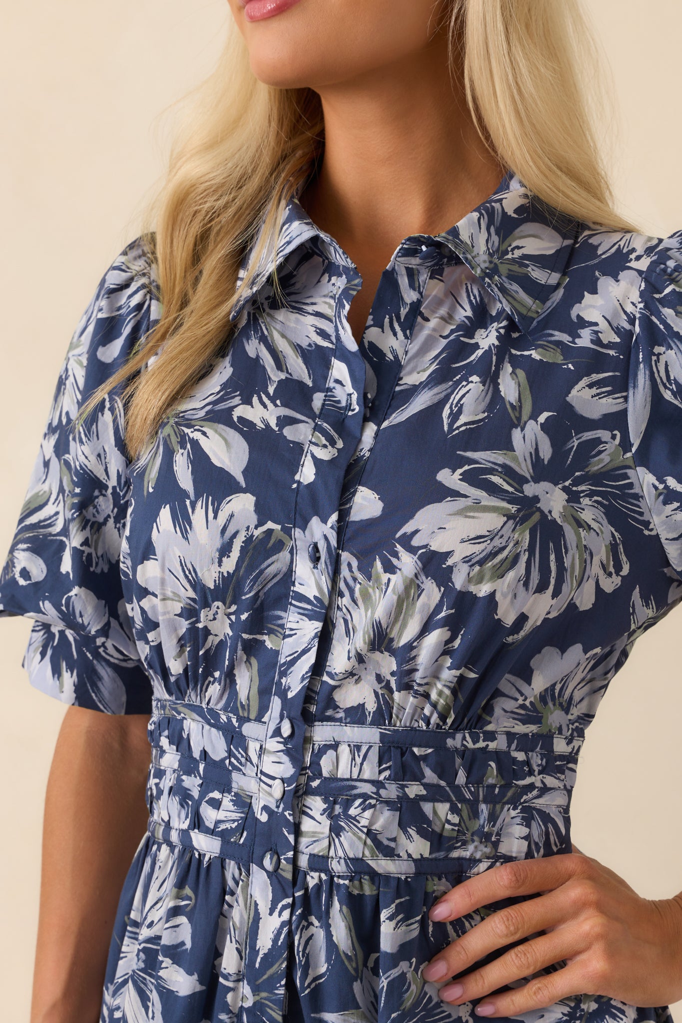 A close-up detail of the ruched waist panel, floral print, and functional button cuffs.