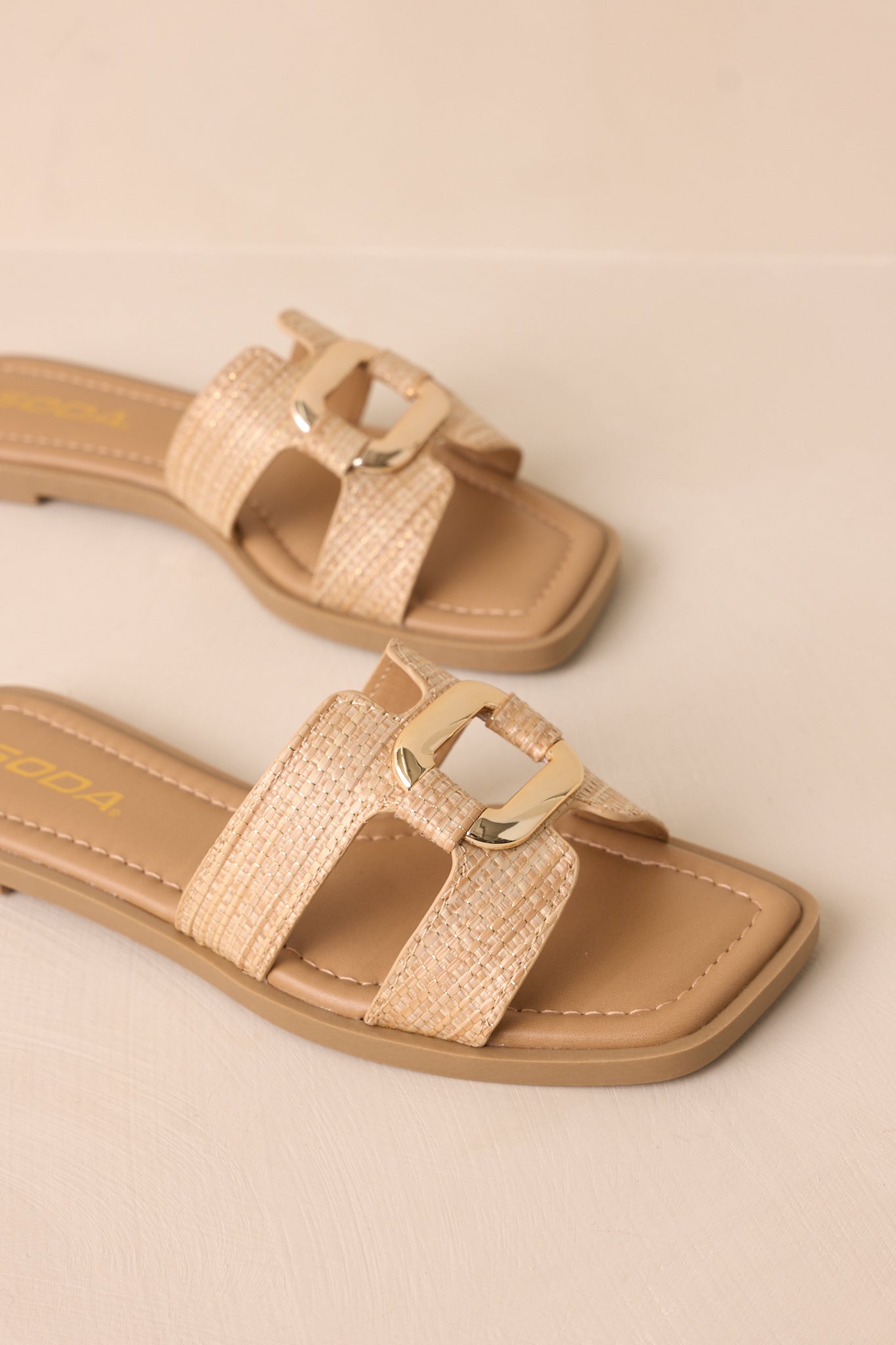 A close-up of the sandal, emphasizing the cutout strap pattern and smooth tan material.