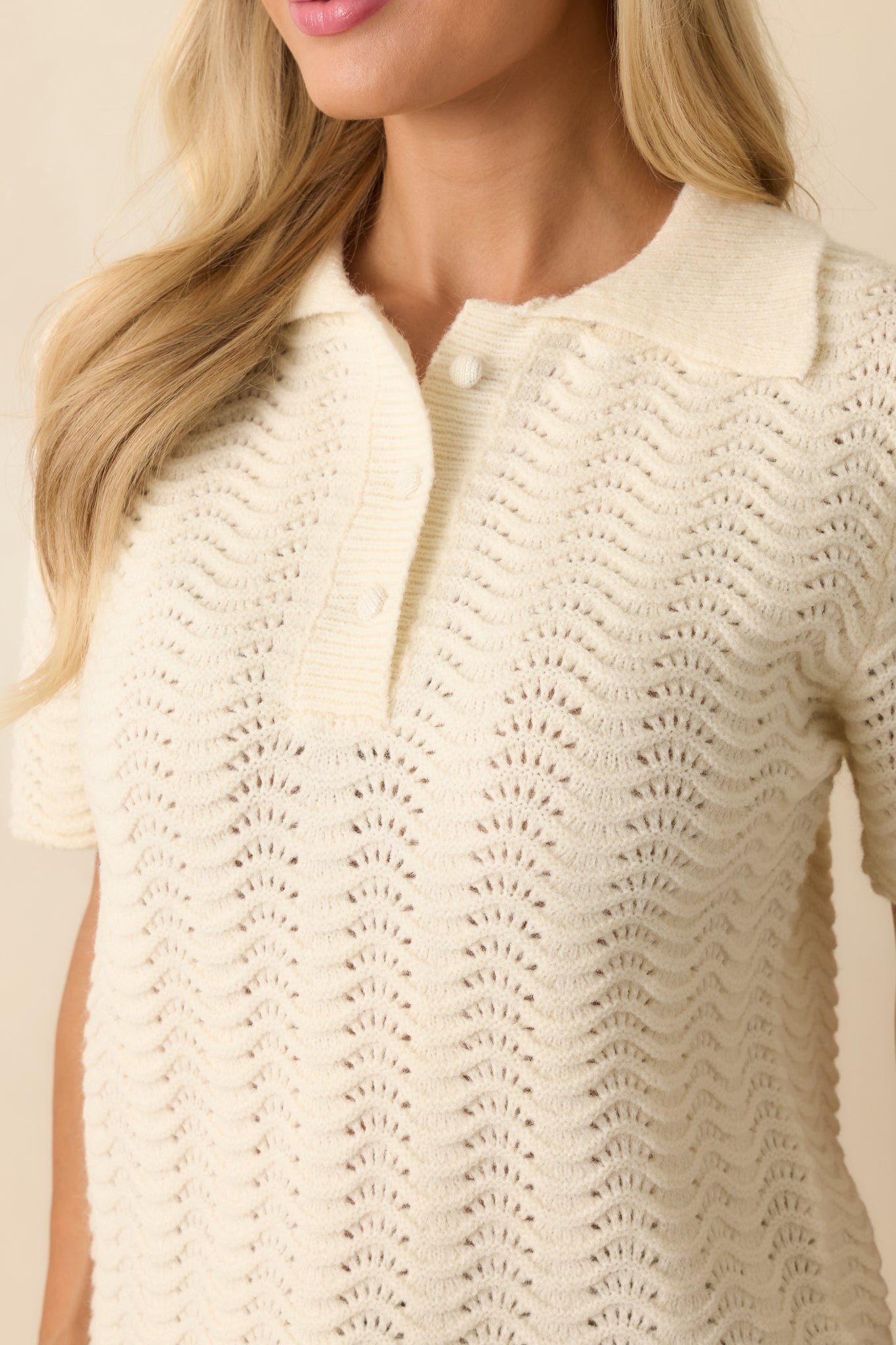 Close-up detail showing the scalloped pointelle knit texture and stitching around the placket and collar.