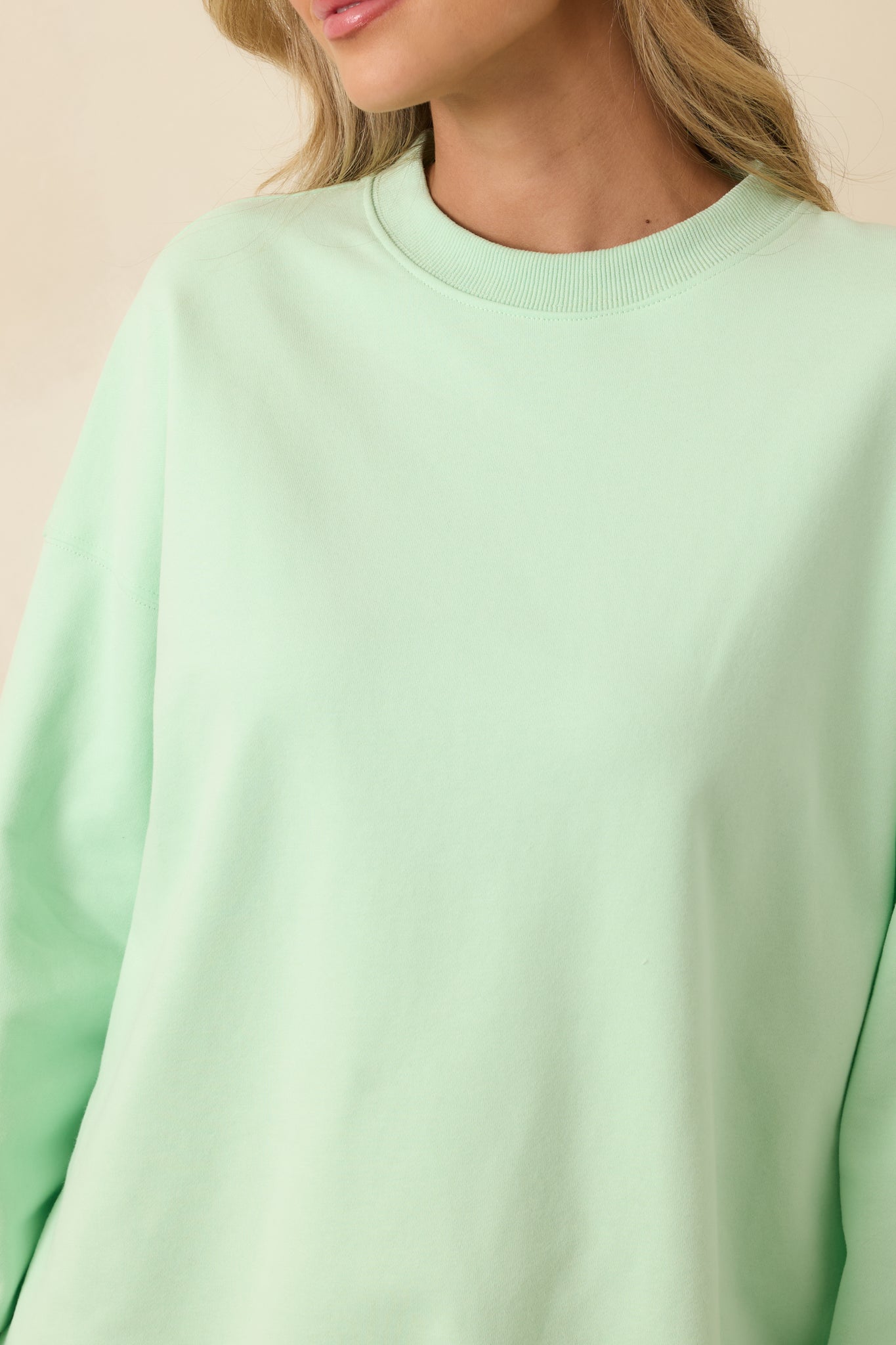 Plush mint green knit fabric close-up showing ribbed trim craftsmanship.