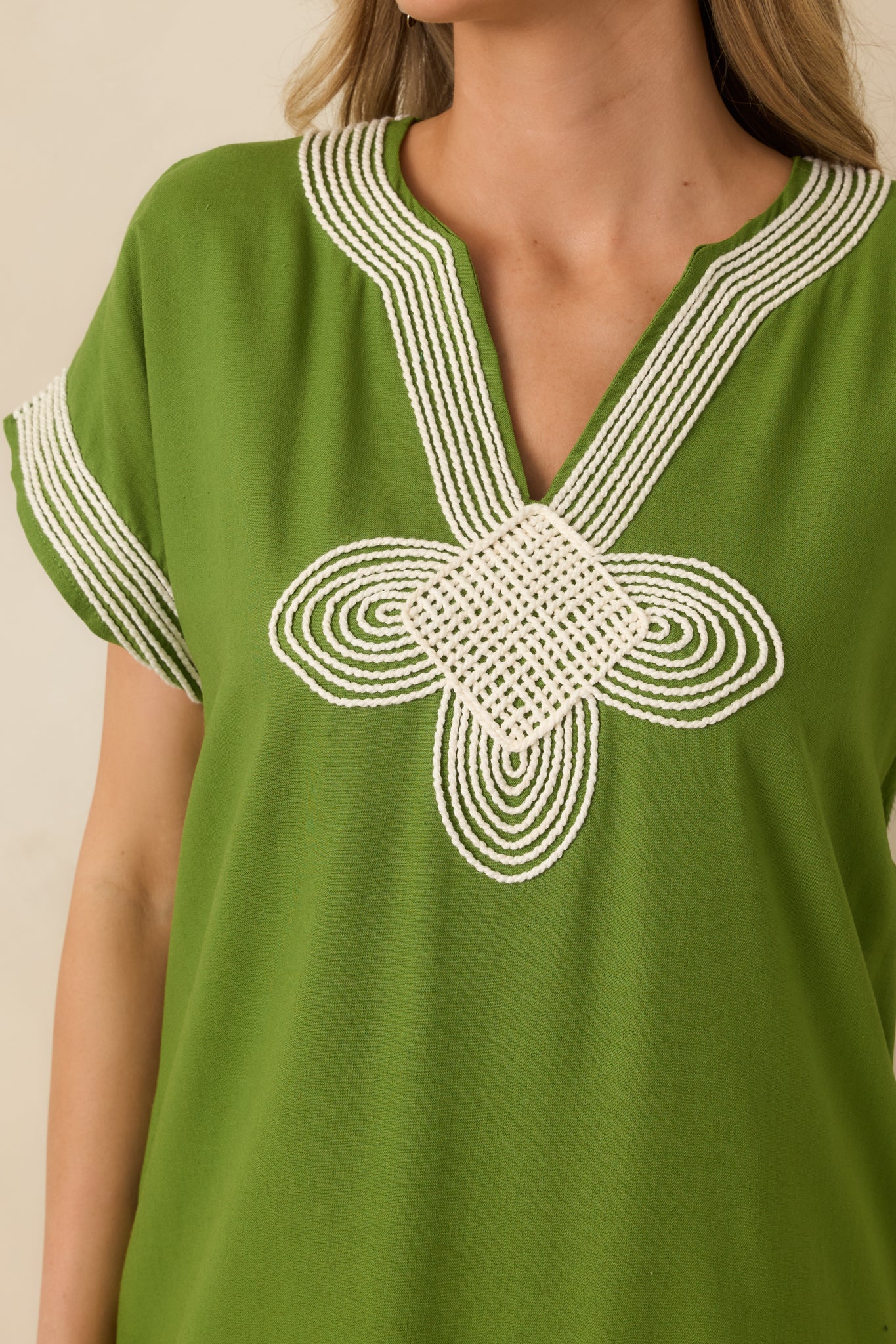 Close-up of the green dress showing the contrast embroidery along the neckline and chest.