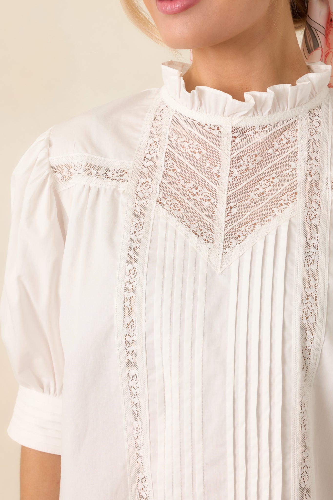 Close-up of the white blouse showing the pintuck fabric texture, lace trim, and banded cuff detail.