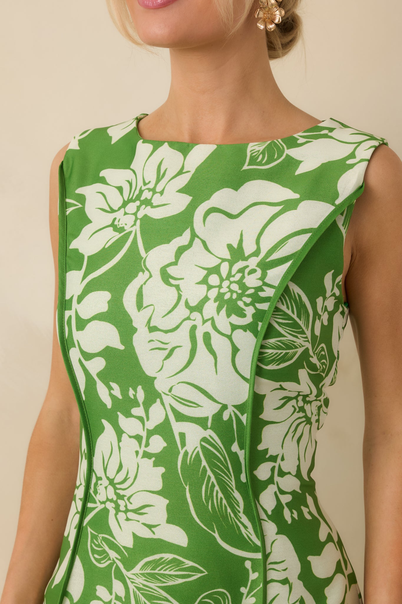 Close-up of the green floral midi dress showing the vertical seam detailing, structured bodice, and fabric texture.
