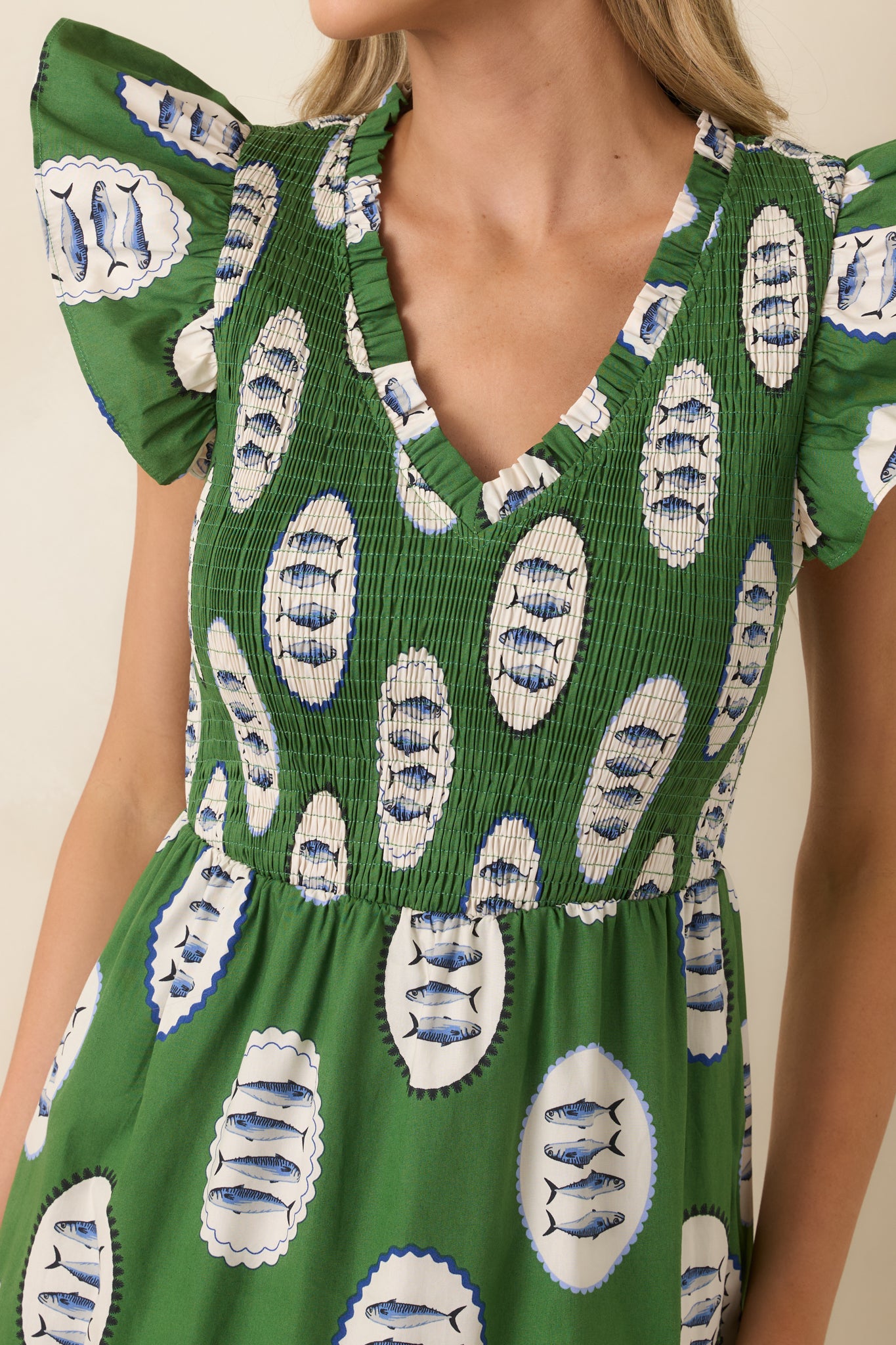 Close-up of green fish print maxi dress showing smocked bodice, V-neckline, and detailed medallion pattern