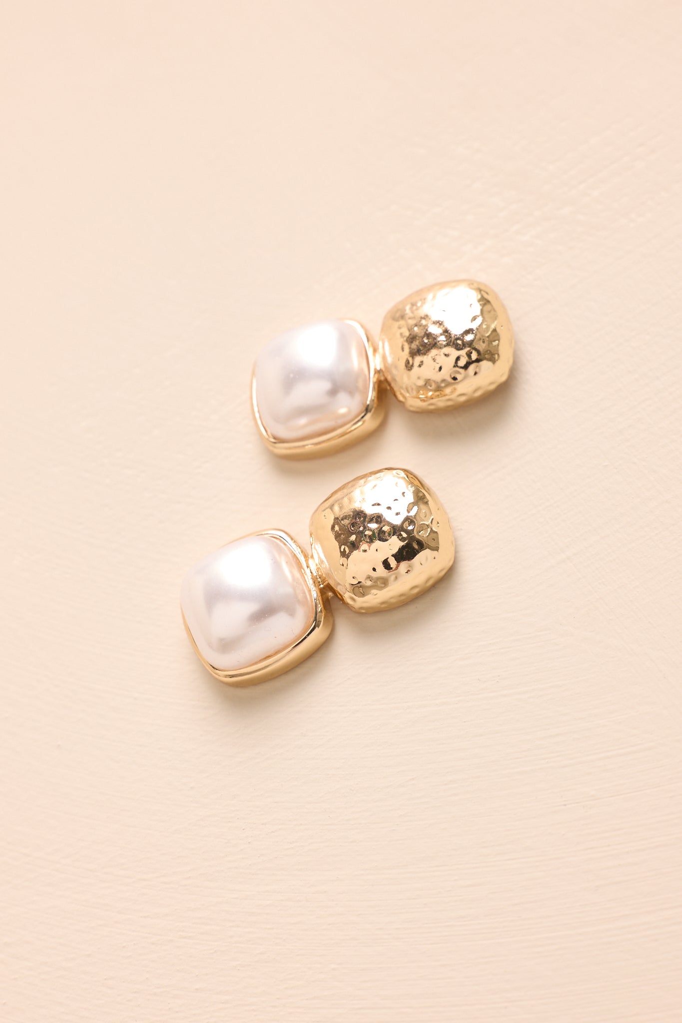 Close-up of the textured gold square stud, ivory faux pearl drop, and detailed earring design.