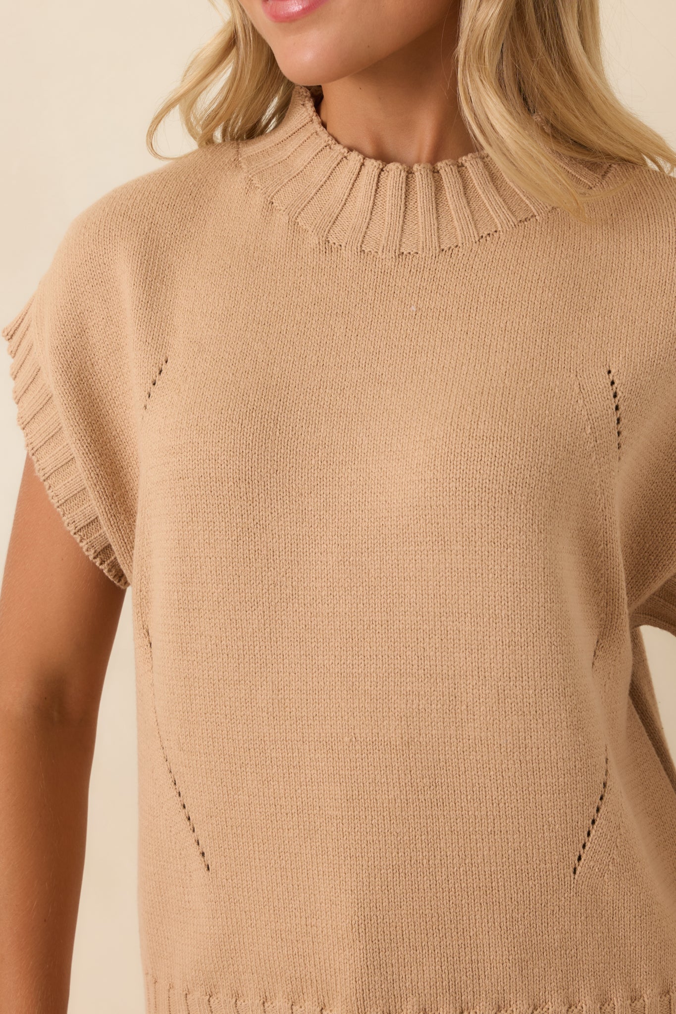 Close-up of the tan knit sweater highlighting the mock neckline, ribbed trim, soft knit texture, and fine stitch detailing.