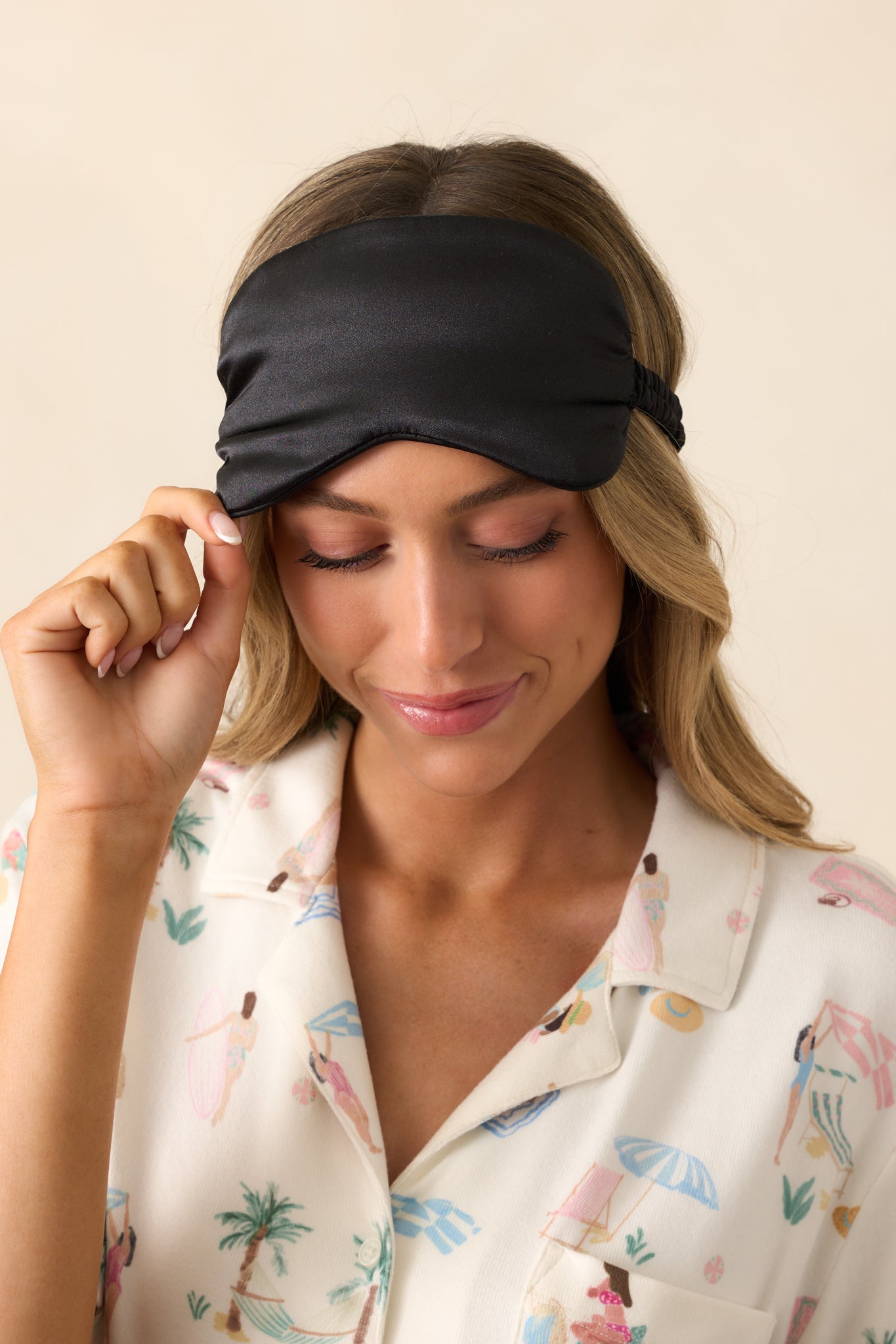 A close-up view of the black satin eye mask, showcasing its smooth fabric and contoured design for comfort.