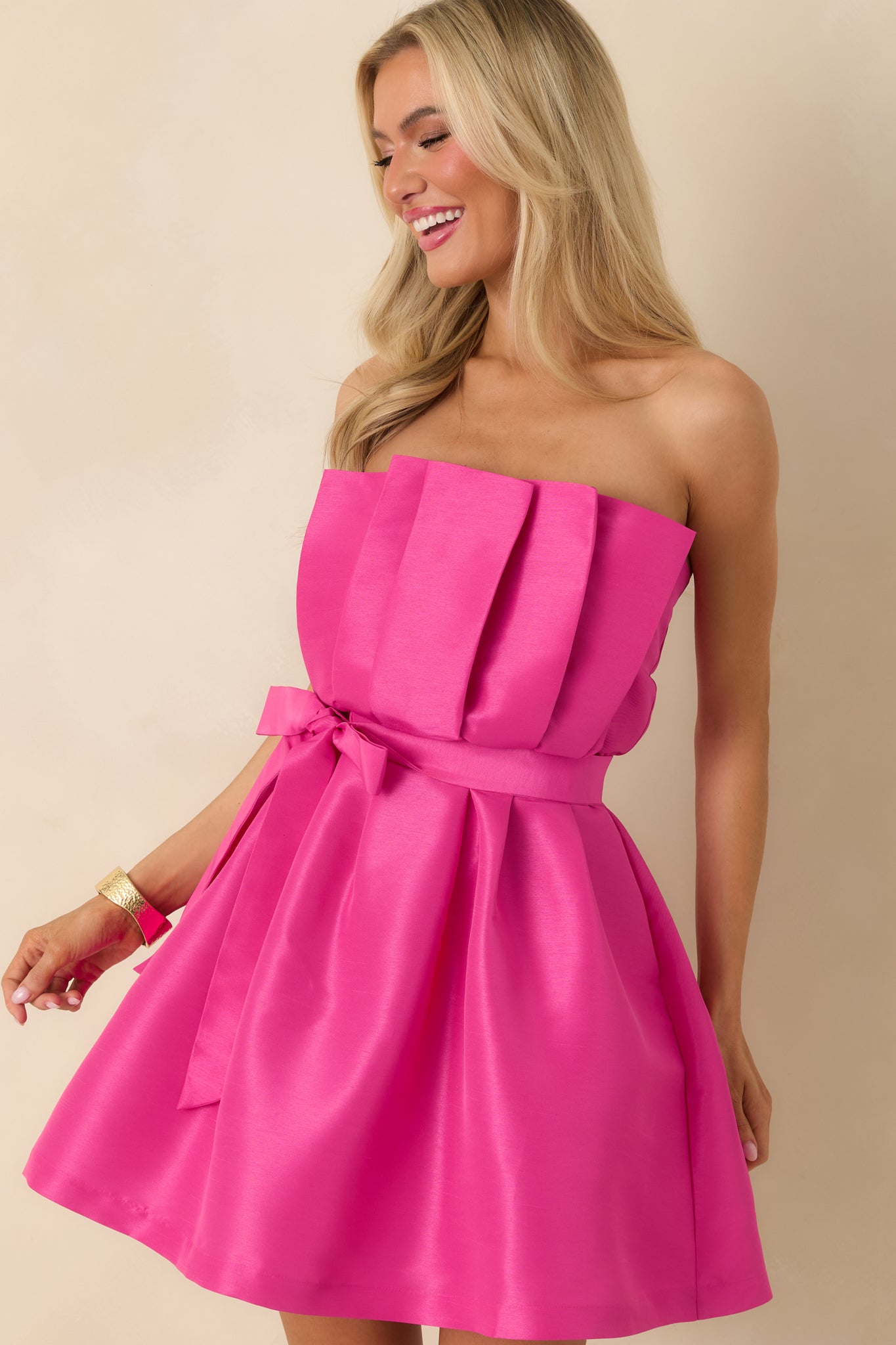 Close-in view of the waist area showing the strapless design and sash tied neatly across the fuchsia dress.
