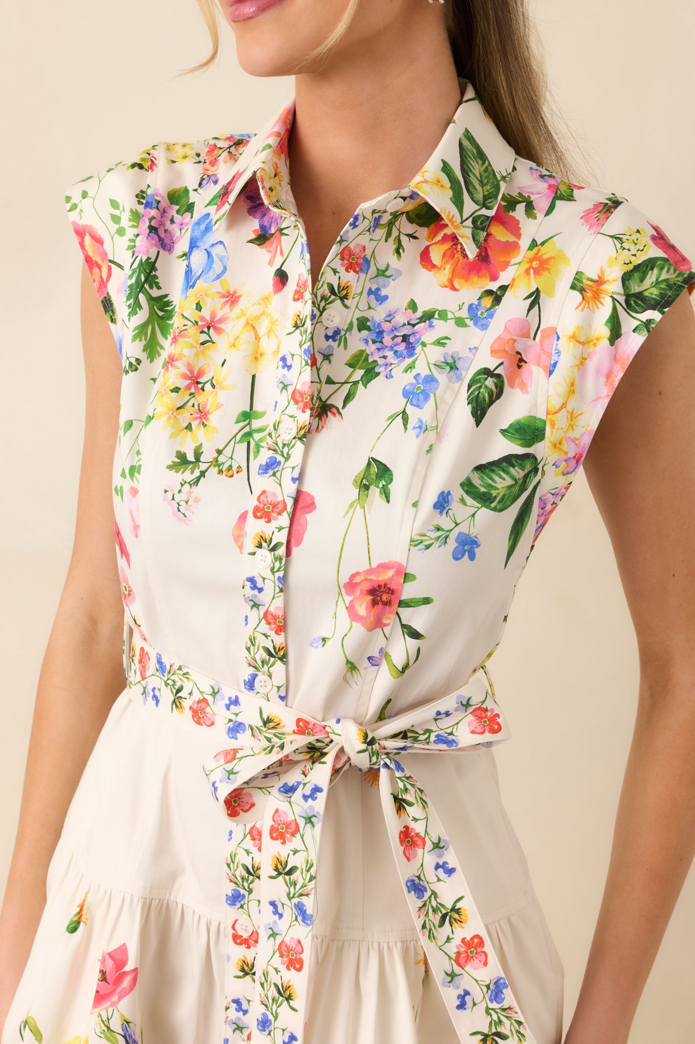 Close-up of the white floral mini dress showing the button-front closure, collar, and fabric texture.