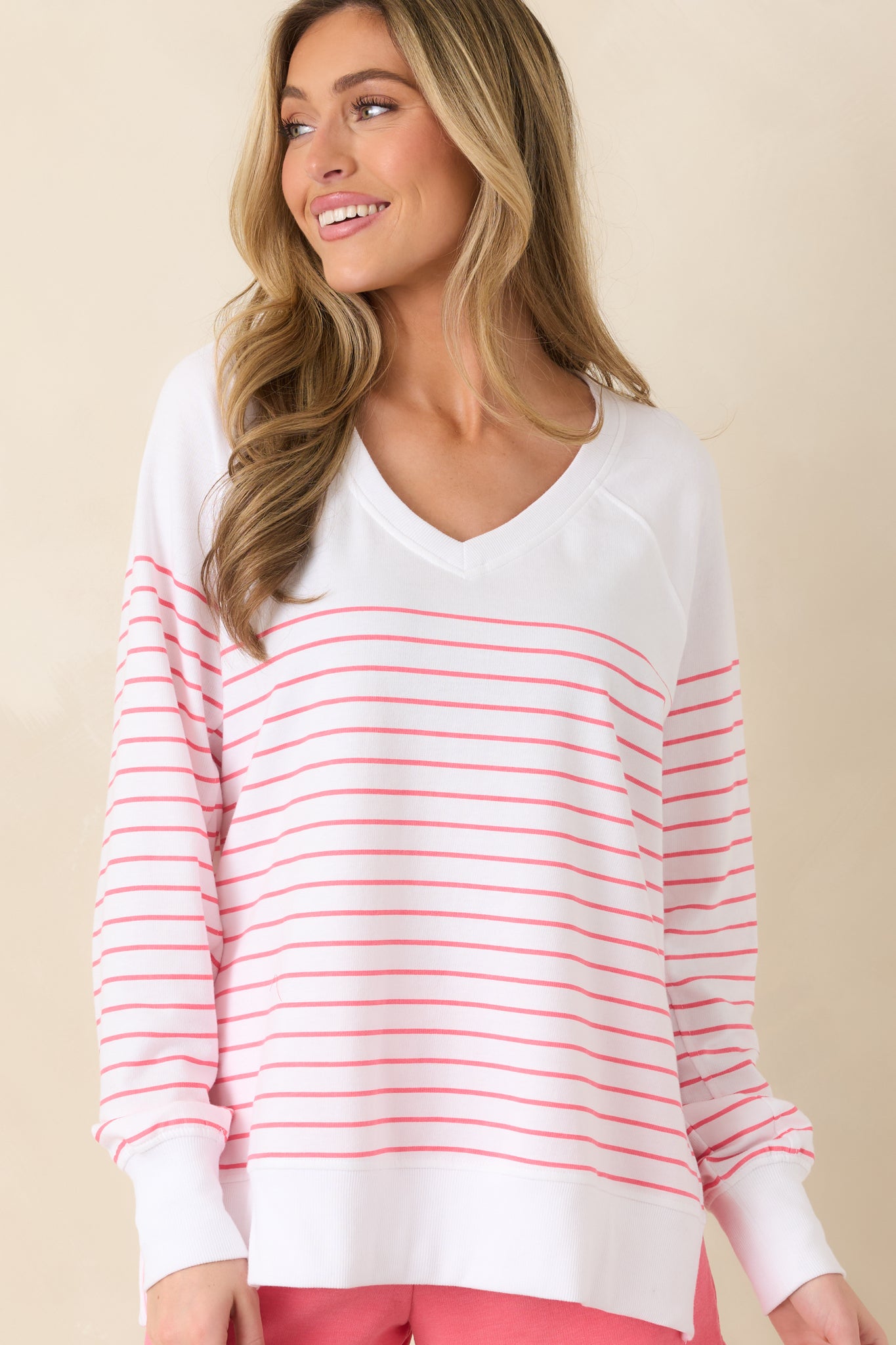 Close view of the V-neckline and horizontal stripe detailing on the white pullover.