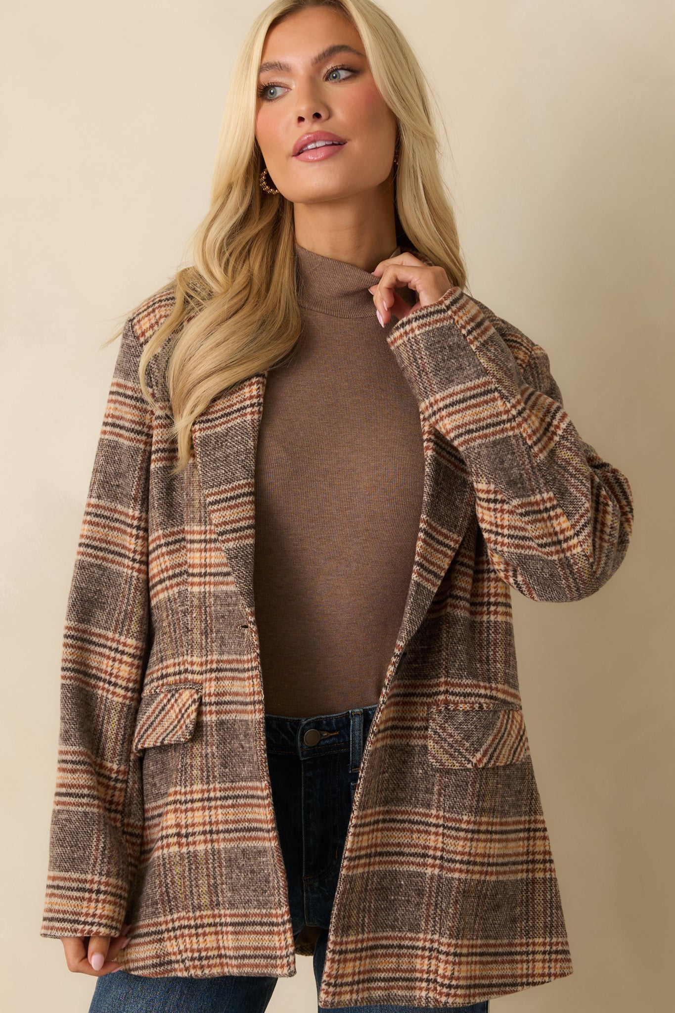Close view of the front of the brown plaid overcoat, emphasizing the button closure and collared neckline.