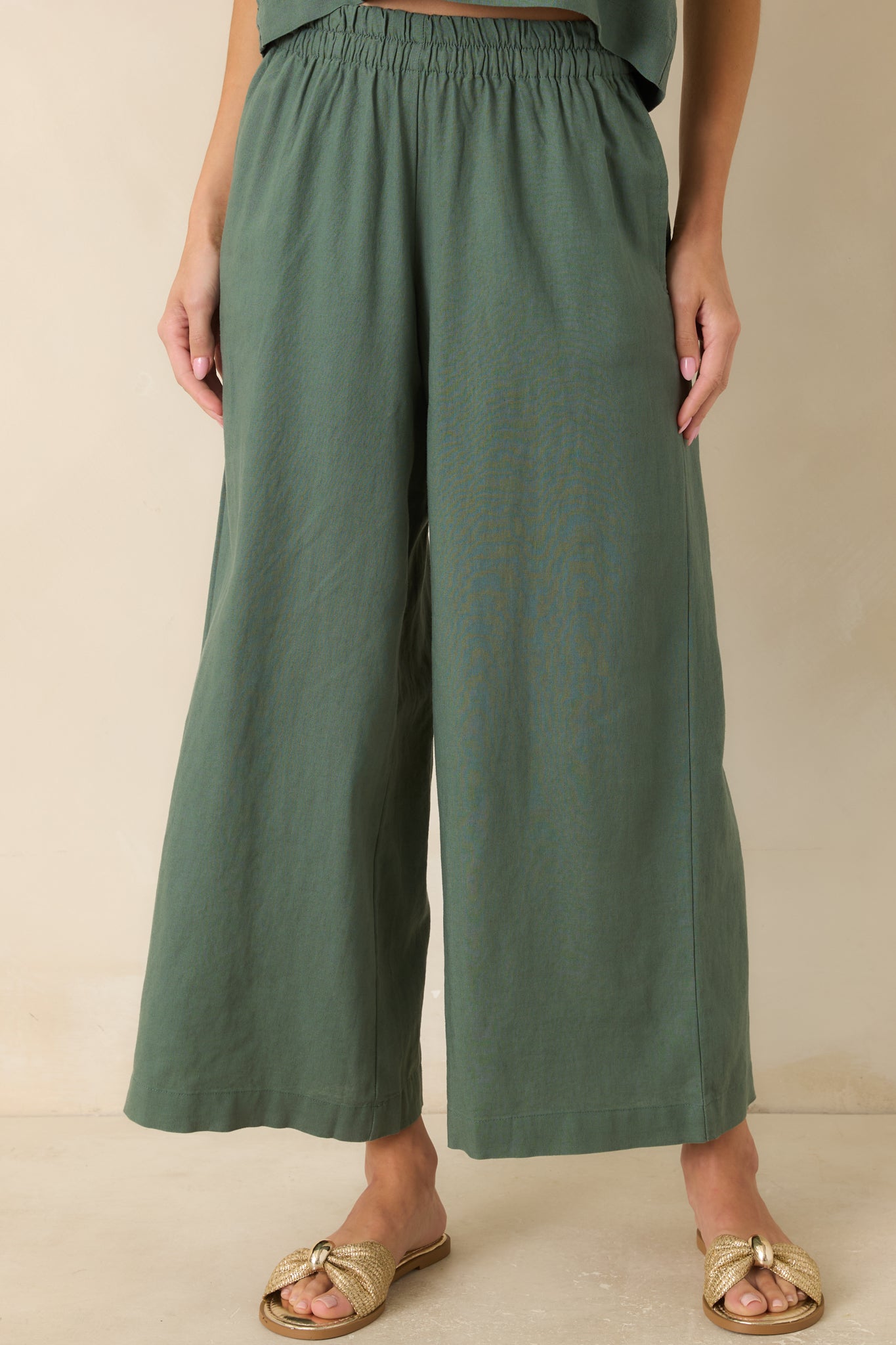 Close view of the green wide-leg pants highlighting the high-rise elastic waistband and smooth linen rayon blend texture.