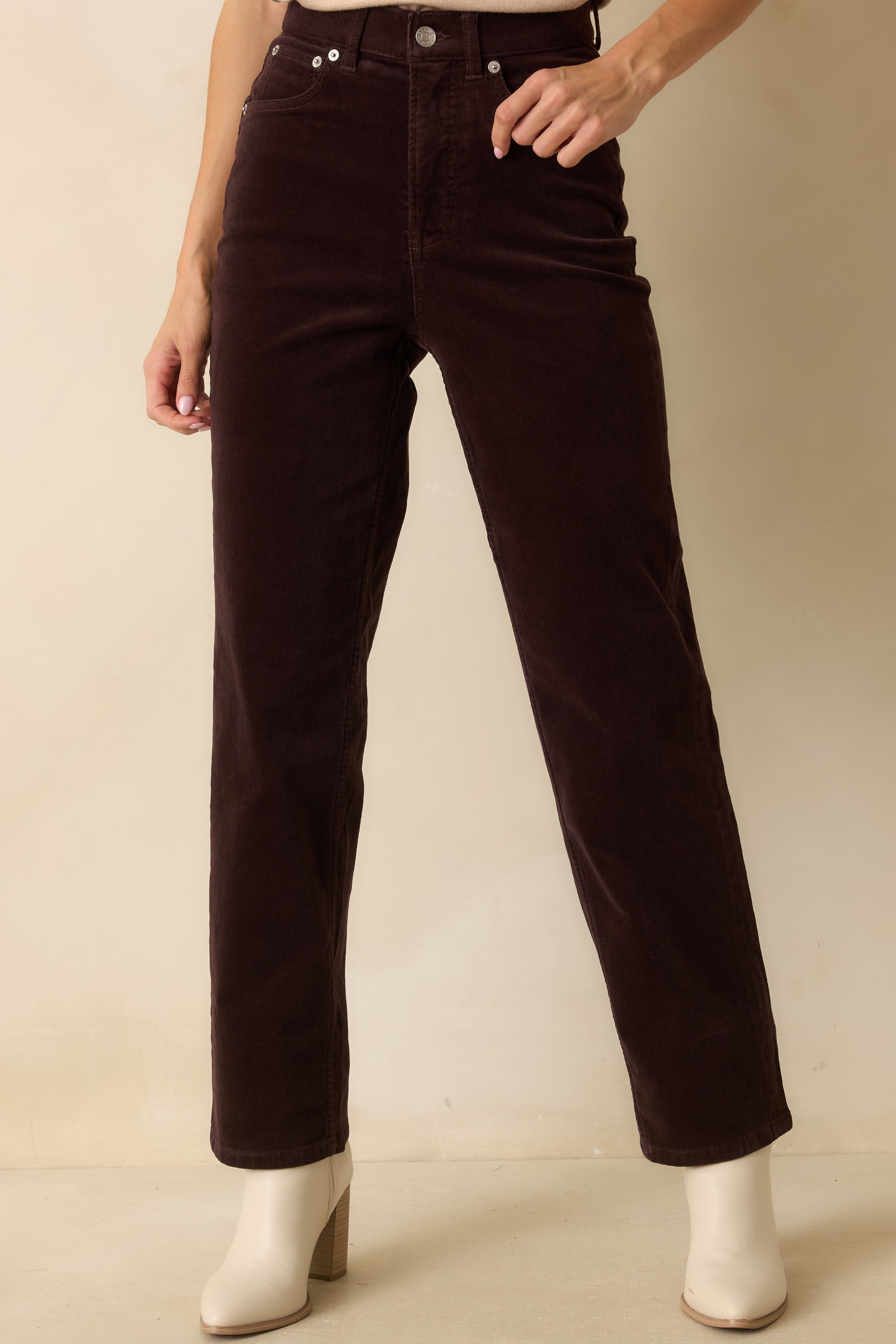 Close view of the high-rise waist and tailored fit of the brown corduroy jeans.