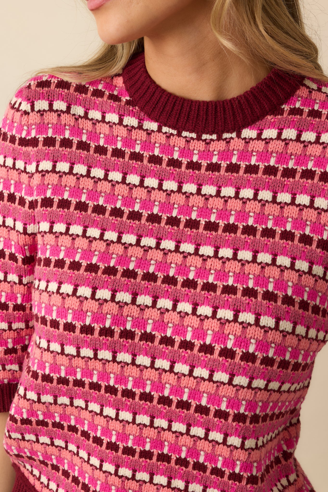 A close view reveals the knit texture, ribbed trim at the neckline, cuffs, and hem, and vibrant multi-stripe pattern.