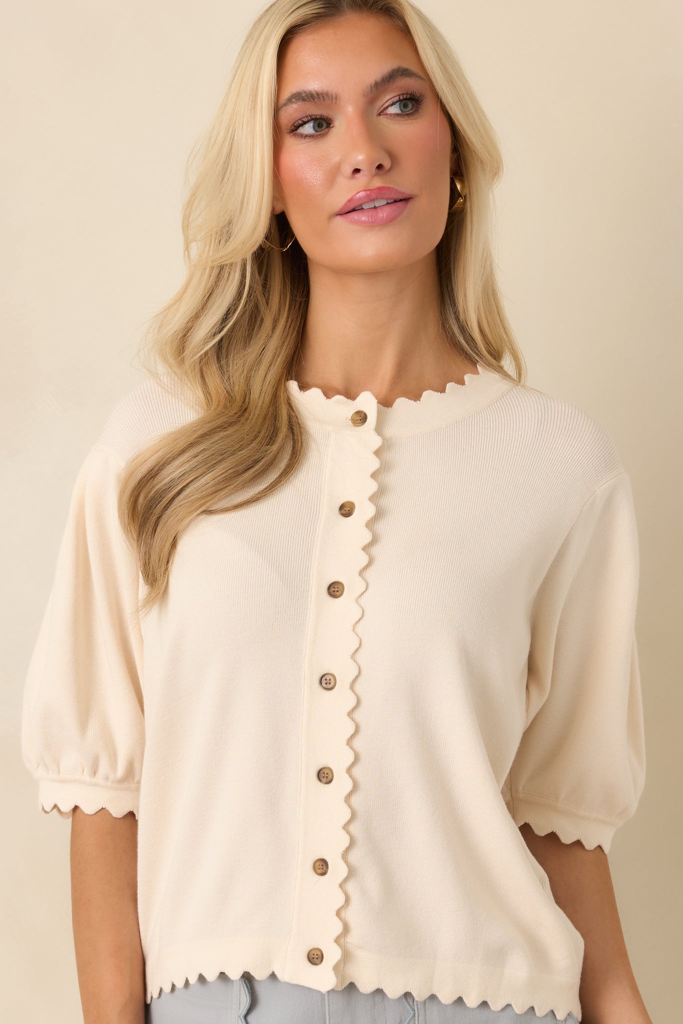 Zoomed view of the button placket highlighting scalloped trim and the soft, airy ivory knit texture.
