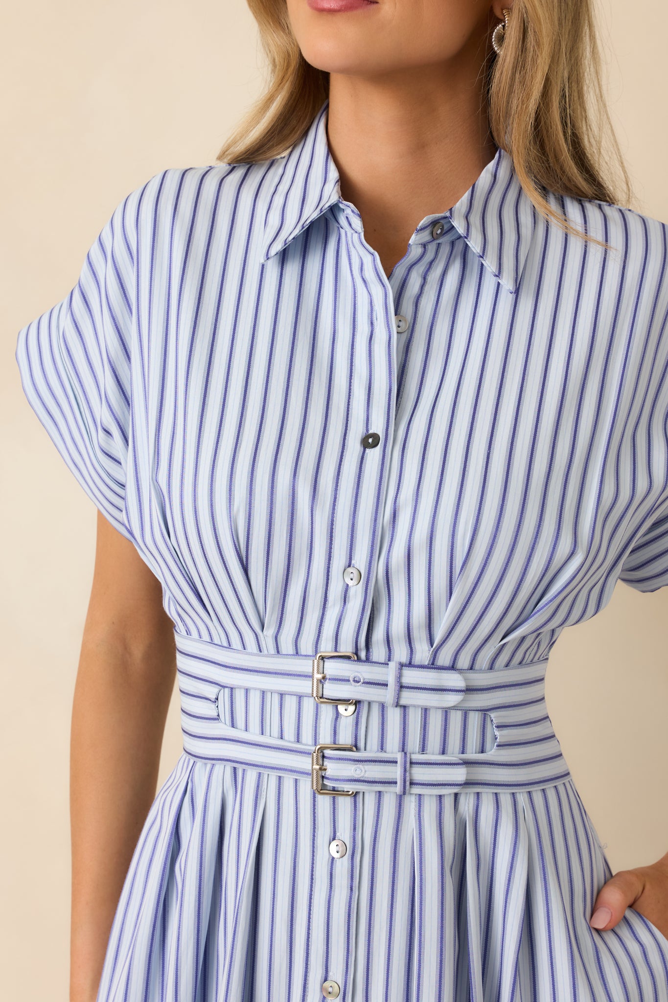 Close view of the blue dress fabric highlighting the crisp vertical stripe contrast, button stitching, and cuffed sleeve knit.