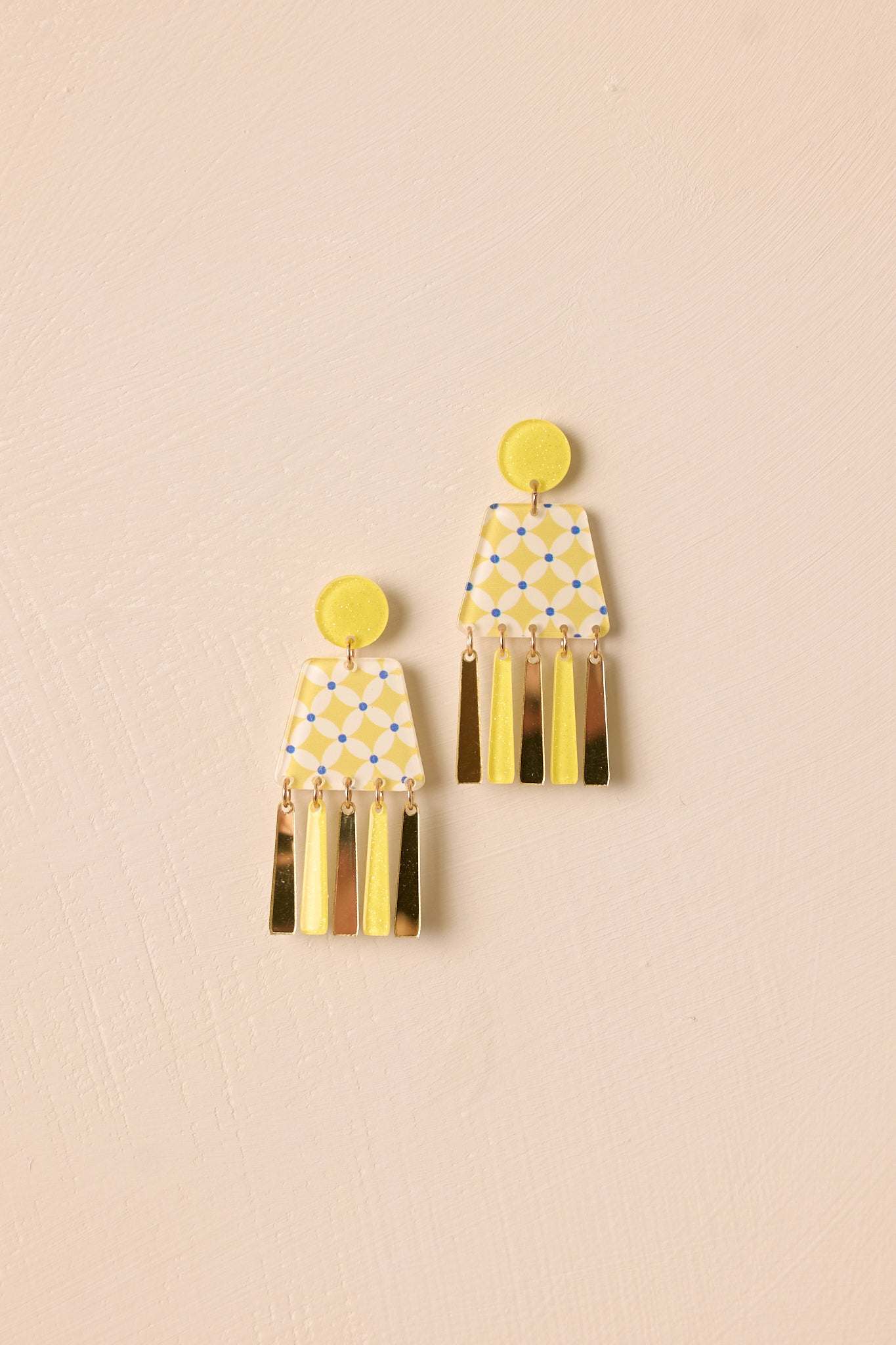 A close-up view of the yellow acrylic earrings, highlighting the geometric design and gold hardware connections.
