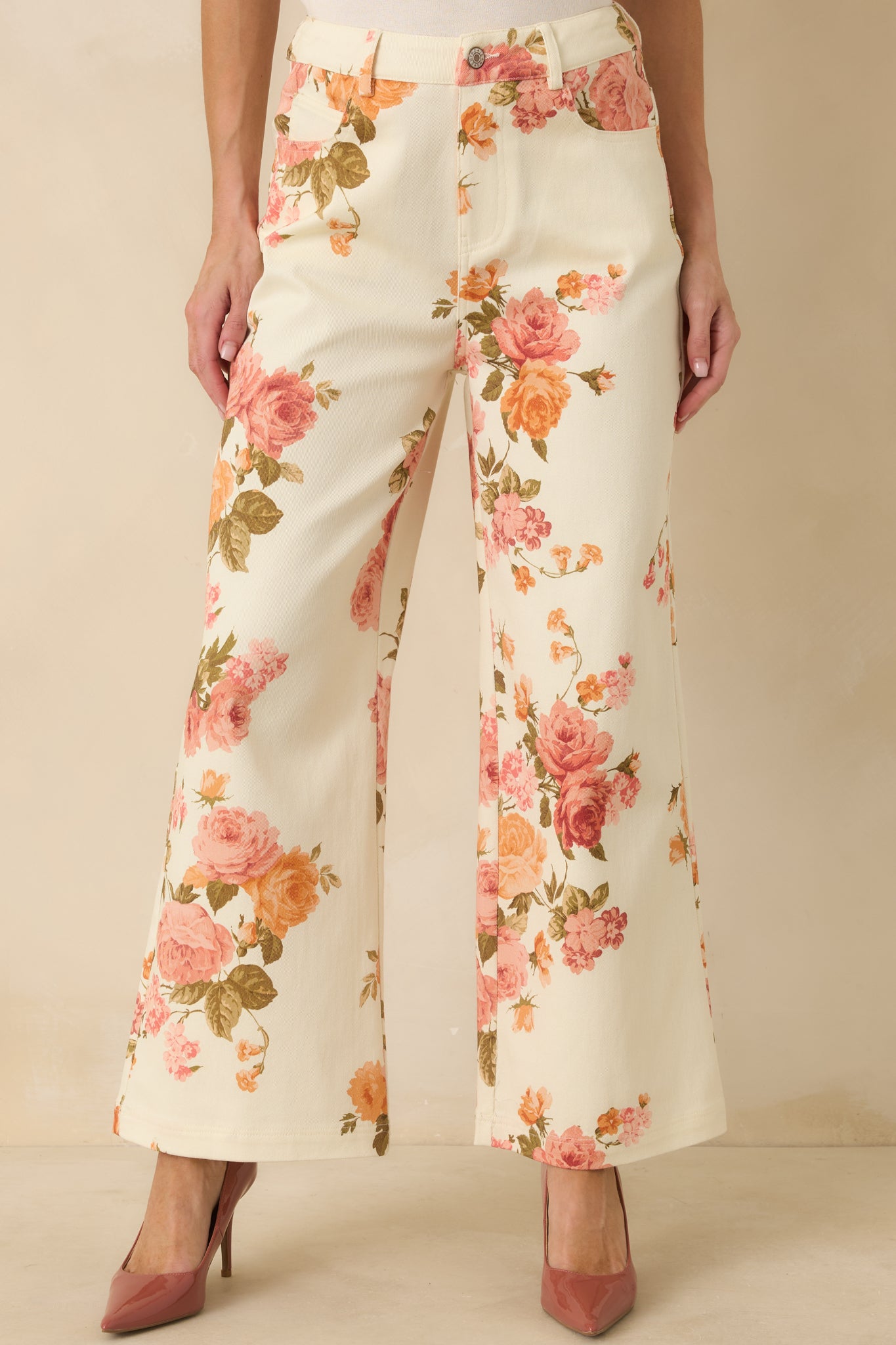 Close view of the high-rise waistband, front button-and-zip closure, and belt loops on the pink floral pants.