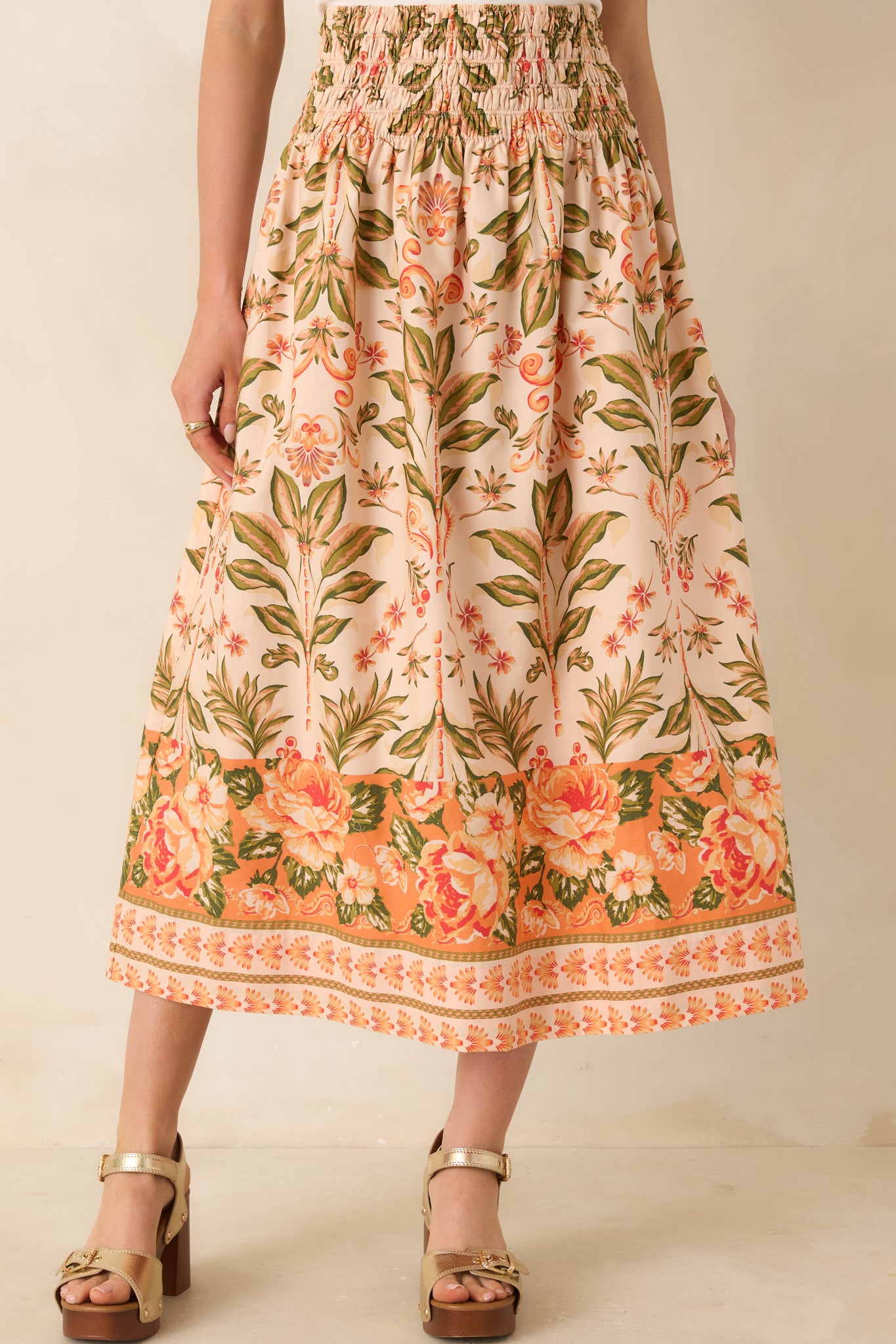 Close view of peach and green floral print with border detail at hem.