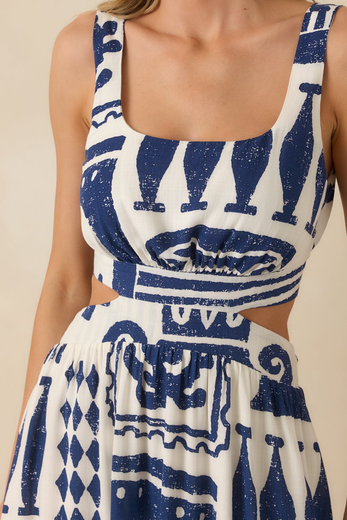 Close view of square neckline, wide strap construction, and side cut-out detail in lightweight woven fabric.