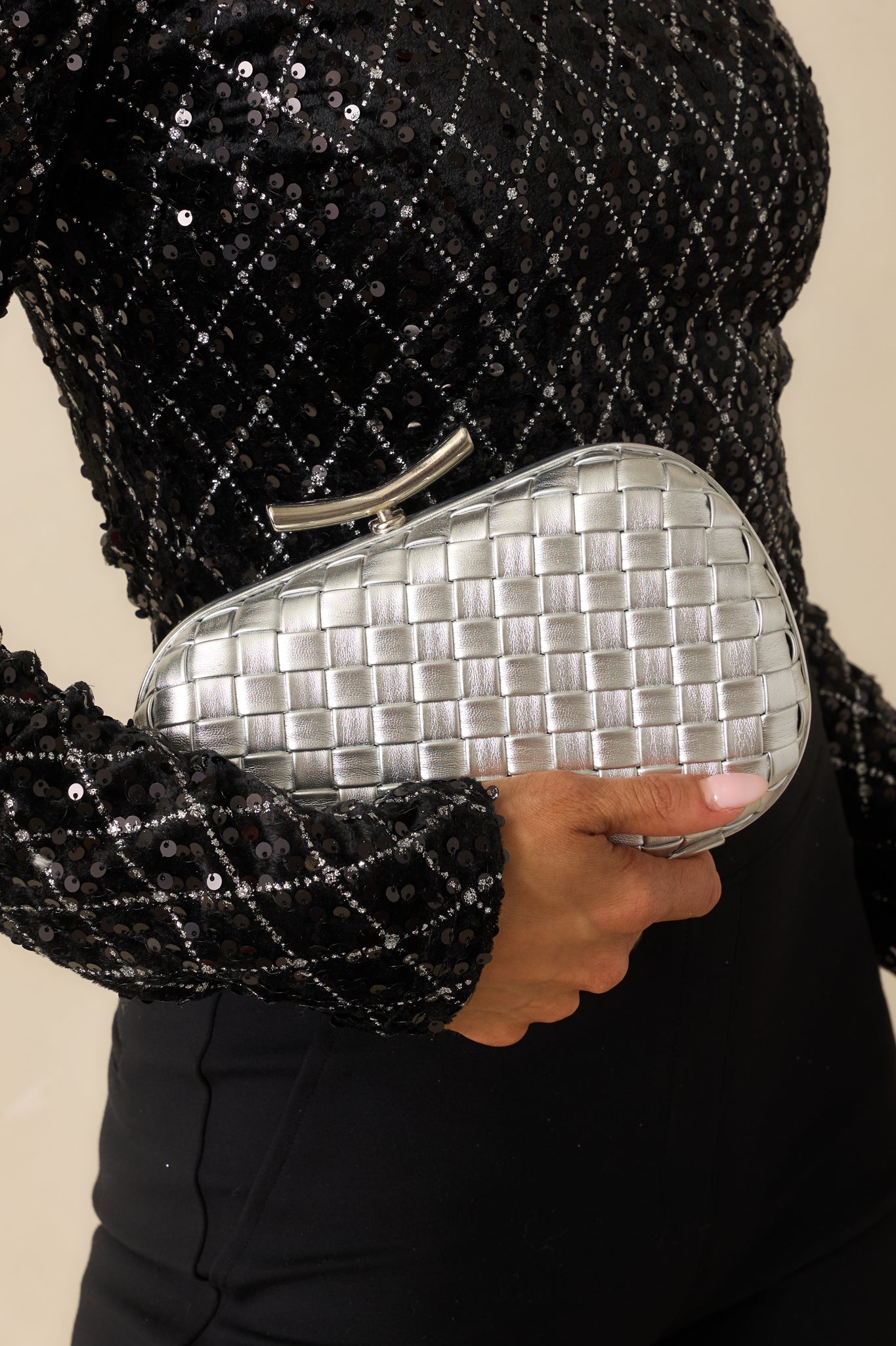 Close view of the clutch’s polished top bar clasp and textured metallic woven exterior.