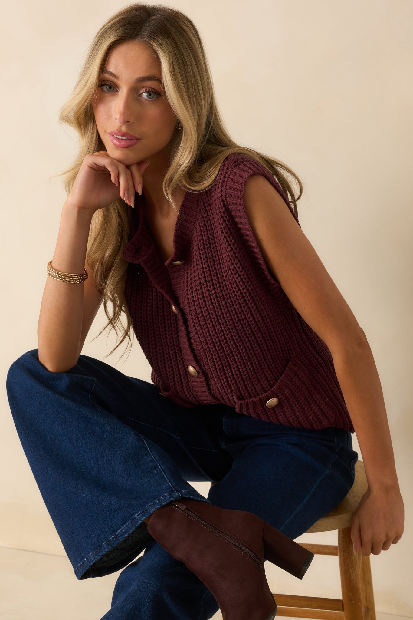Close view of the round neckline and ribbed knit texture on the wine red vest.