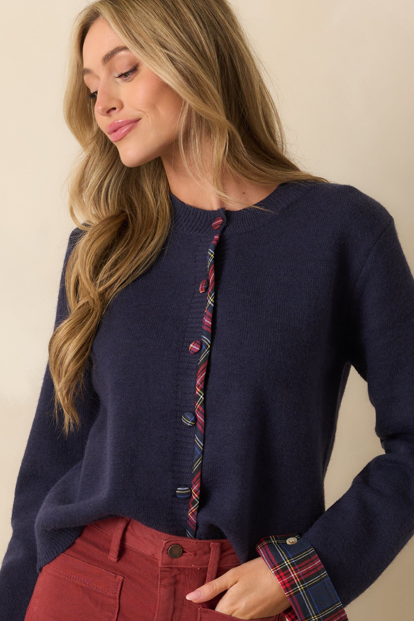 Close view of the covered plaid buttons and tartan placket trim on the navy cardigan.