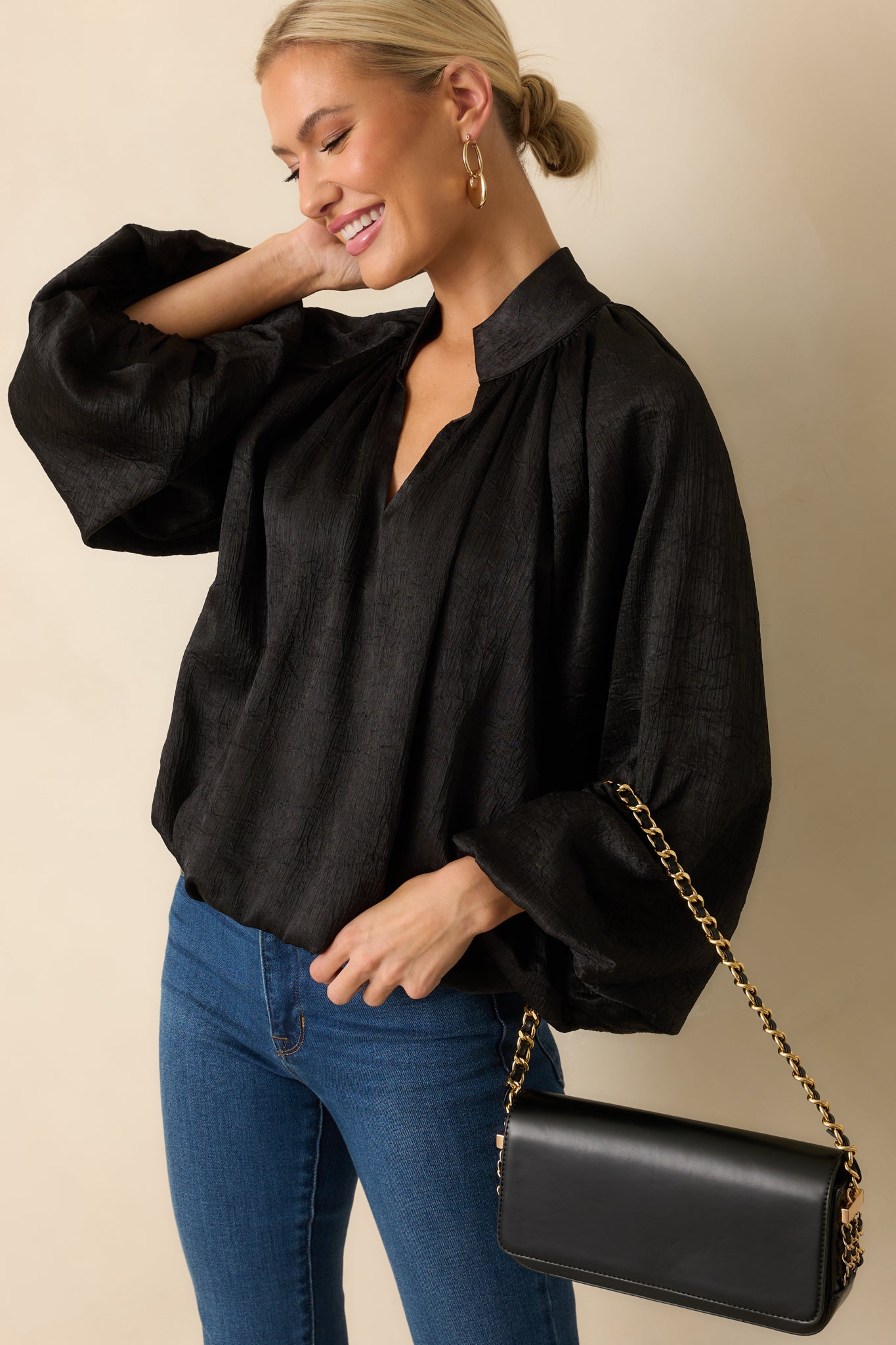Close view of the top’s softly ruched V-neckline and smooth satin texture.