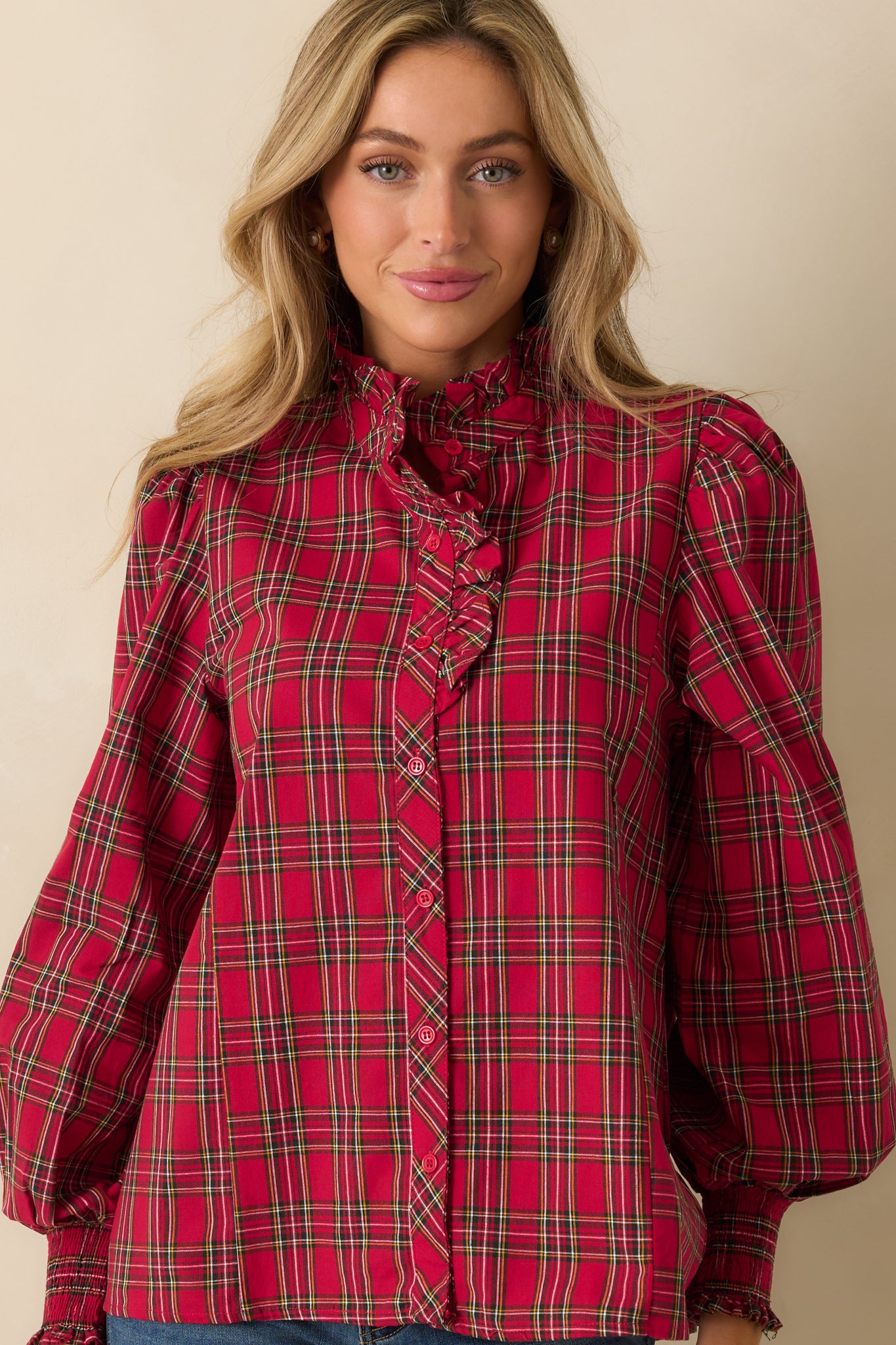 Close view of the ruffle neck detail and button-up front in red plaid fabric.
