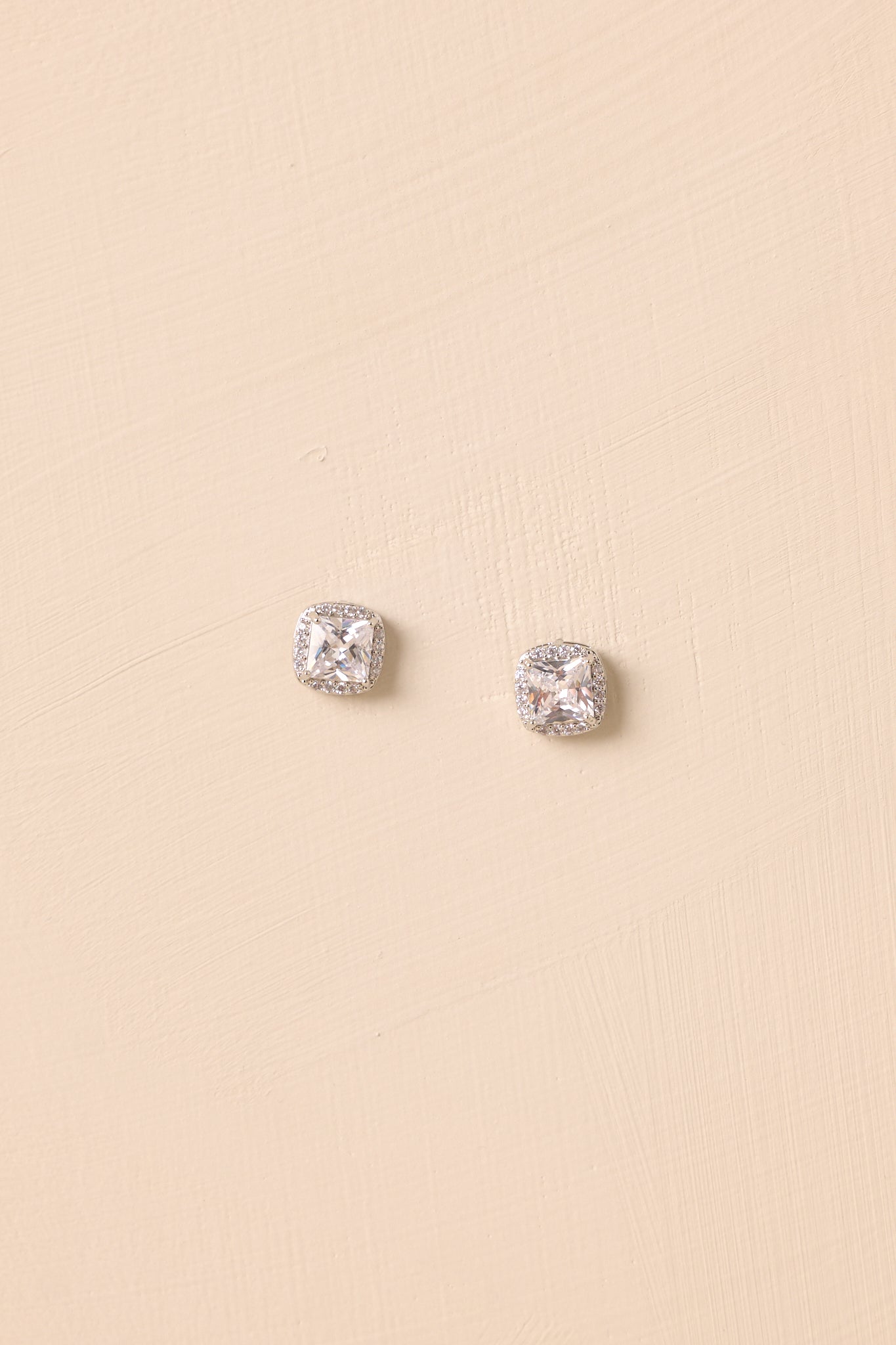 A close view of the silver stud earrings with cushion-cut cubic zirconia centers and pavé halo.