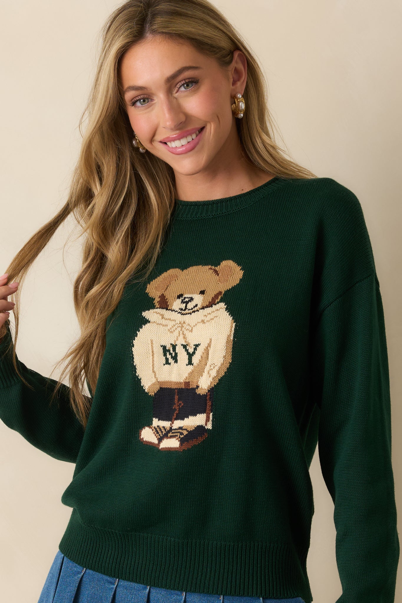 Close view of the teddy bear graphic and ribbed crew neckline on the hunter green sweater.