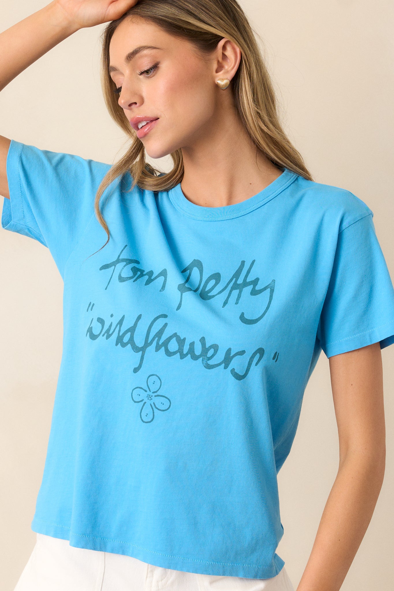 A closer shot of the blue tee’s graphic design, focusing on the reimagined "Wildflowers" record, with the crew neckline and short sleeves visible.