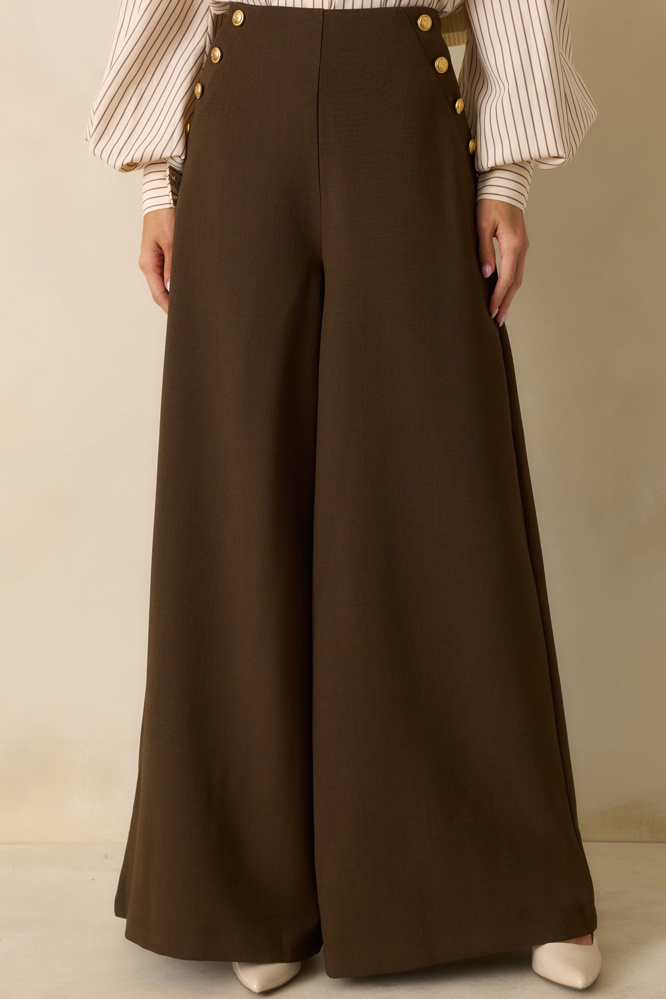 Closer view of the high-rise waistband with decorative gold button accents.