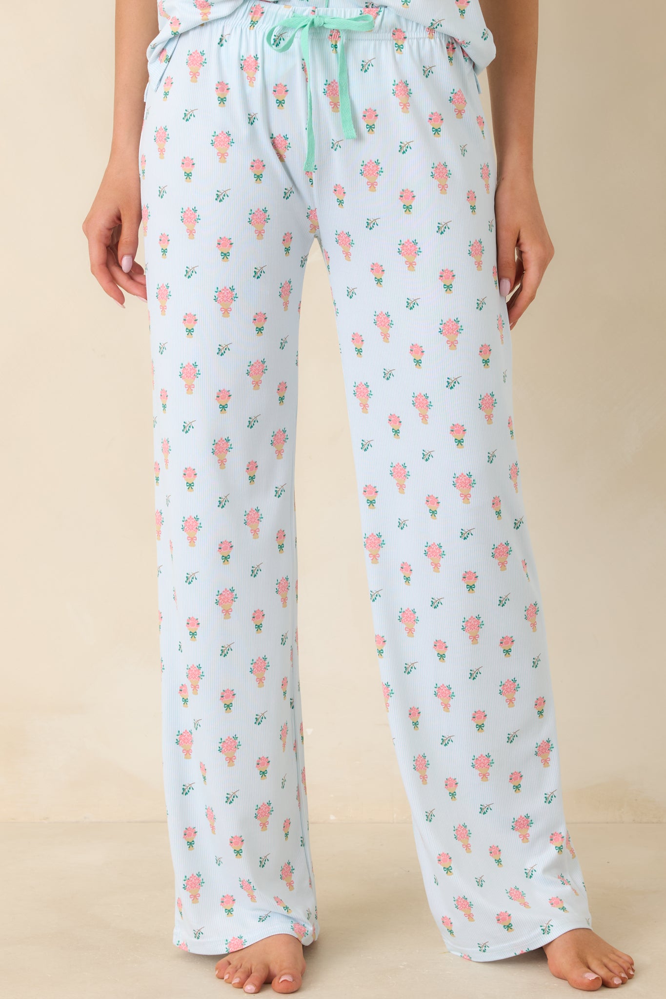 Closer view of the elastic waistband with adjustable drawstring set against the soft green floral fabric.