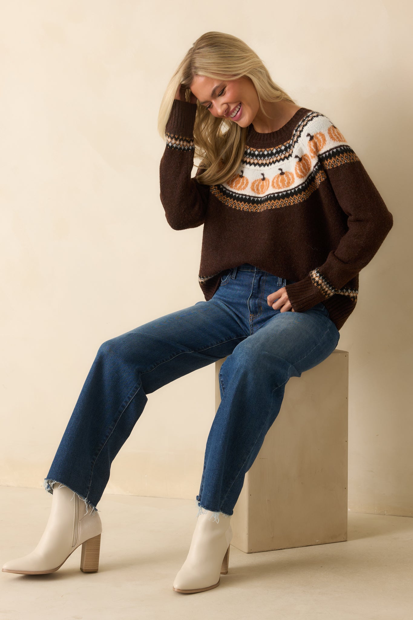 Knit texture and fair isle pumpkin pattern in ivory and orange stand out against the dark brown yarn.