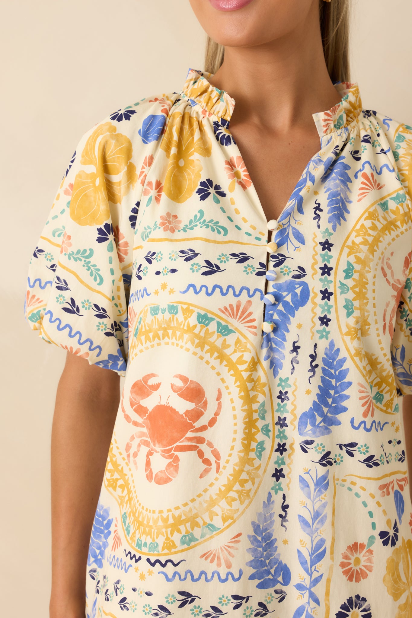 Close-up detail of the mini dress highlighting the colorful coastal patchwork print, decorative buttons, split neckline, and stand collar.