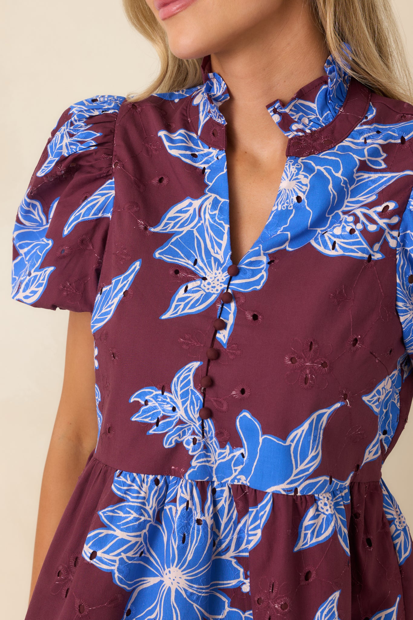 Close-up view of the cobalt blue floral top highlighting the eyelet embroidery, buttons, and ruffle collar.
