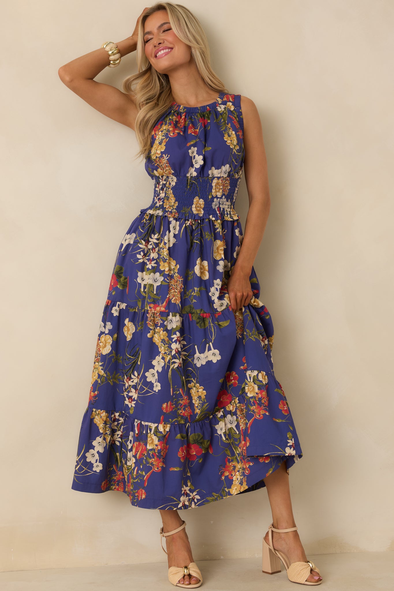 Cobalt blue maxi dress with multicolor floral print, gathered round neckline, sleeveless design, and tiered flowing skirt.