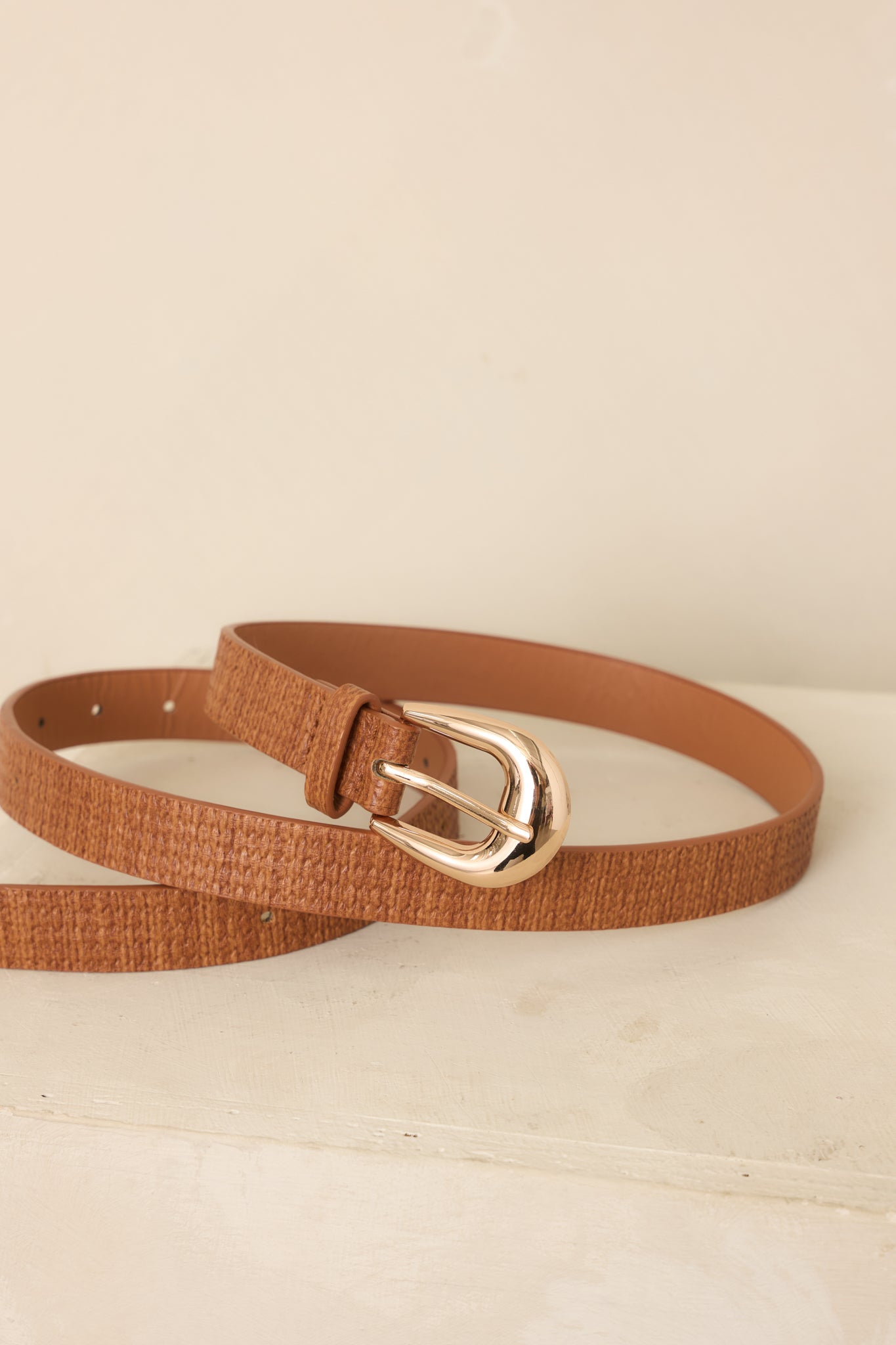 Brown woven-texture belt showcasing its warm cognac hue, polished gold-tone buckle, and adjustable punched-hole closure.