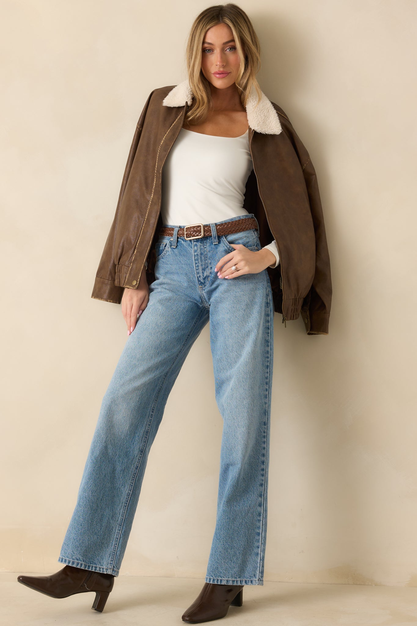 Cognac faux leather bomber jacket presented with long sleeves and a softly structured oversized shape.