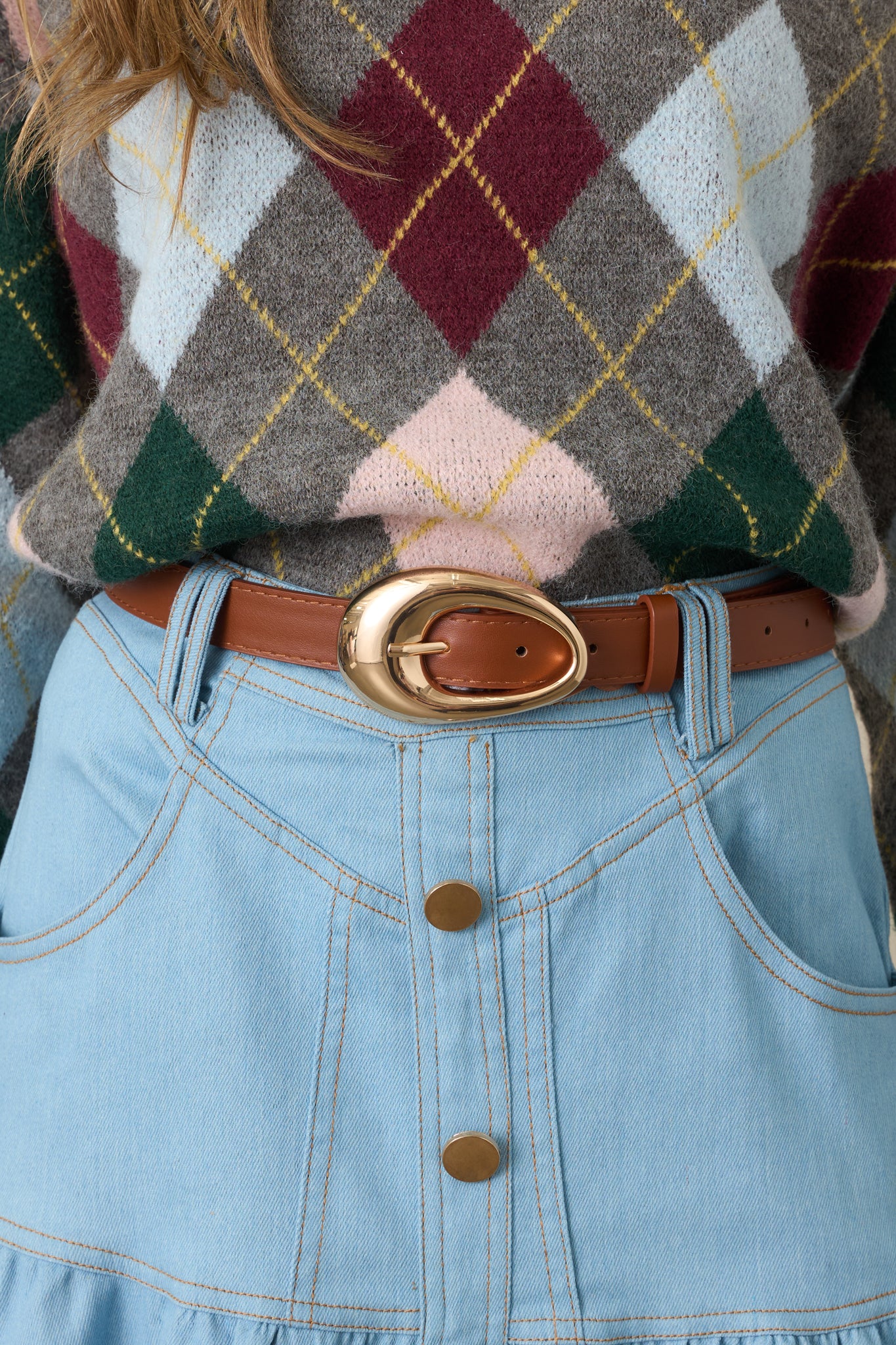 Cognac faux leather belt featuring an oversized polished gold-tone oval buckle and clean, classic strap design.