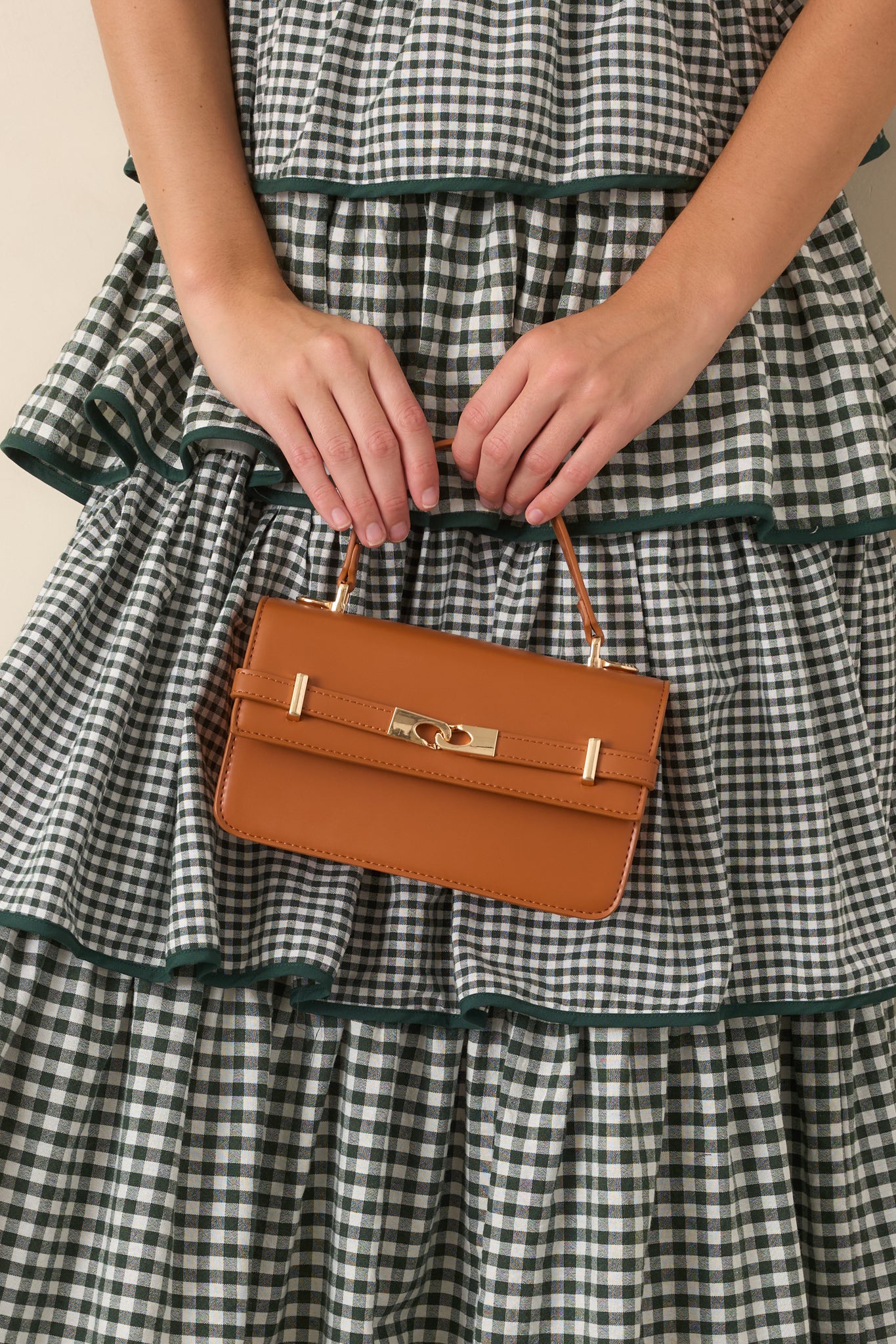 Warm cognac faux leather handbag featuring a structured silhouette, elegant top handle, sophisticated front belt detail, and polished gold-tone hardware.